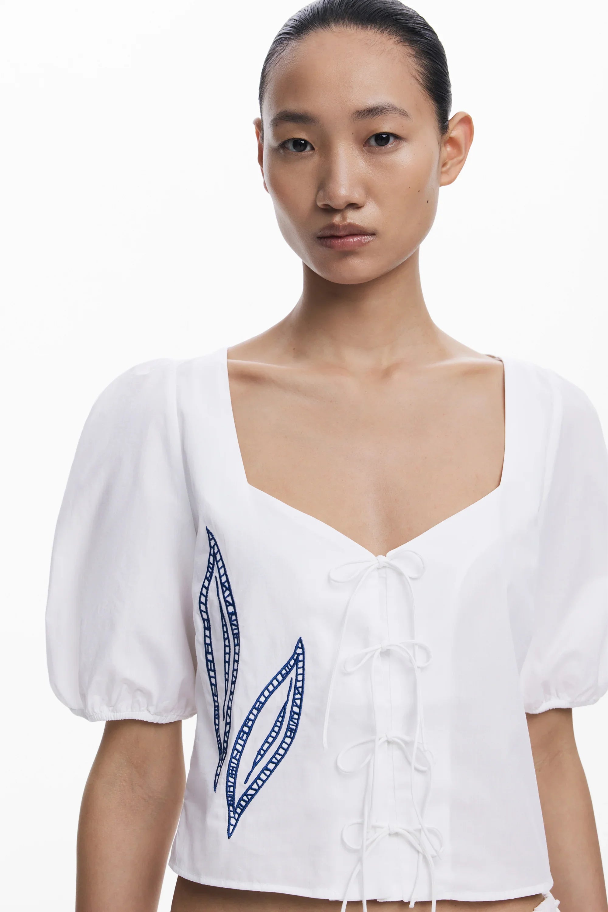 חולצת נשים לבנה עם שרוכים ועיטורי עלים כחולים, אופנה עדכנית באתר CHOZEN