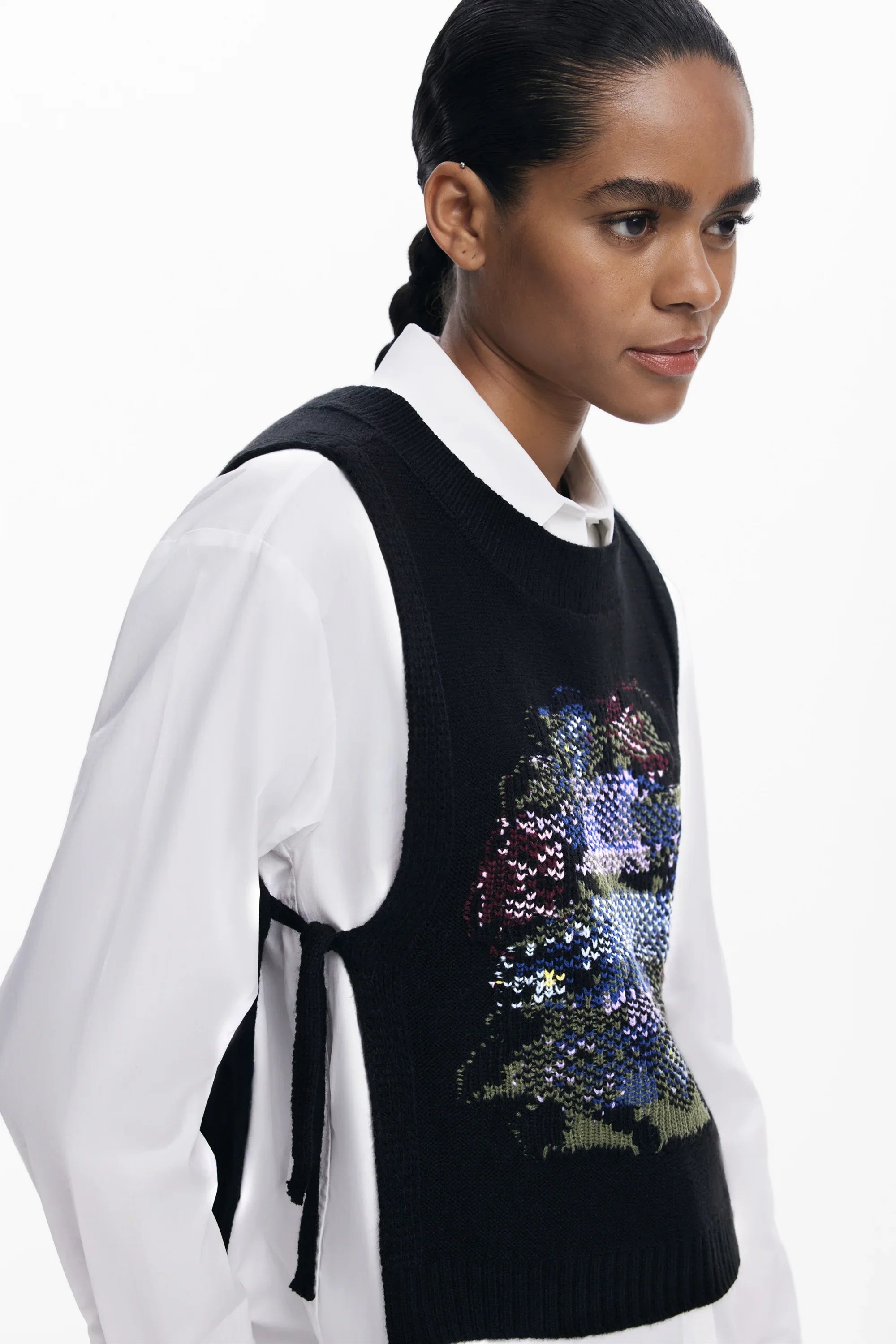 אישה לובשת וסט סרוג שחור עם הדפס פרחוני מעל חולצה לבנה, אופנת CHOZEN