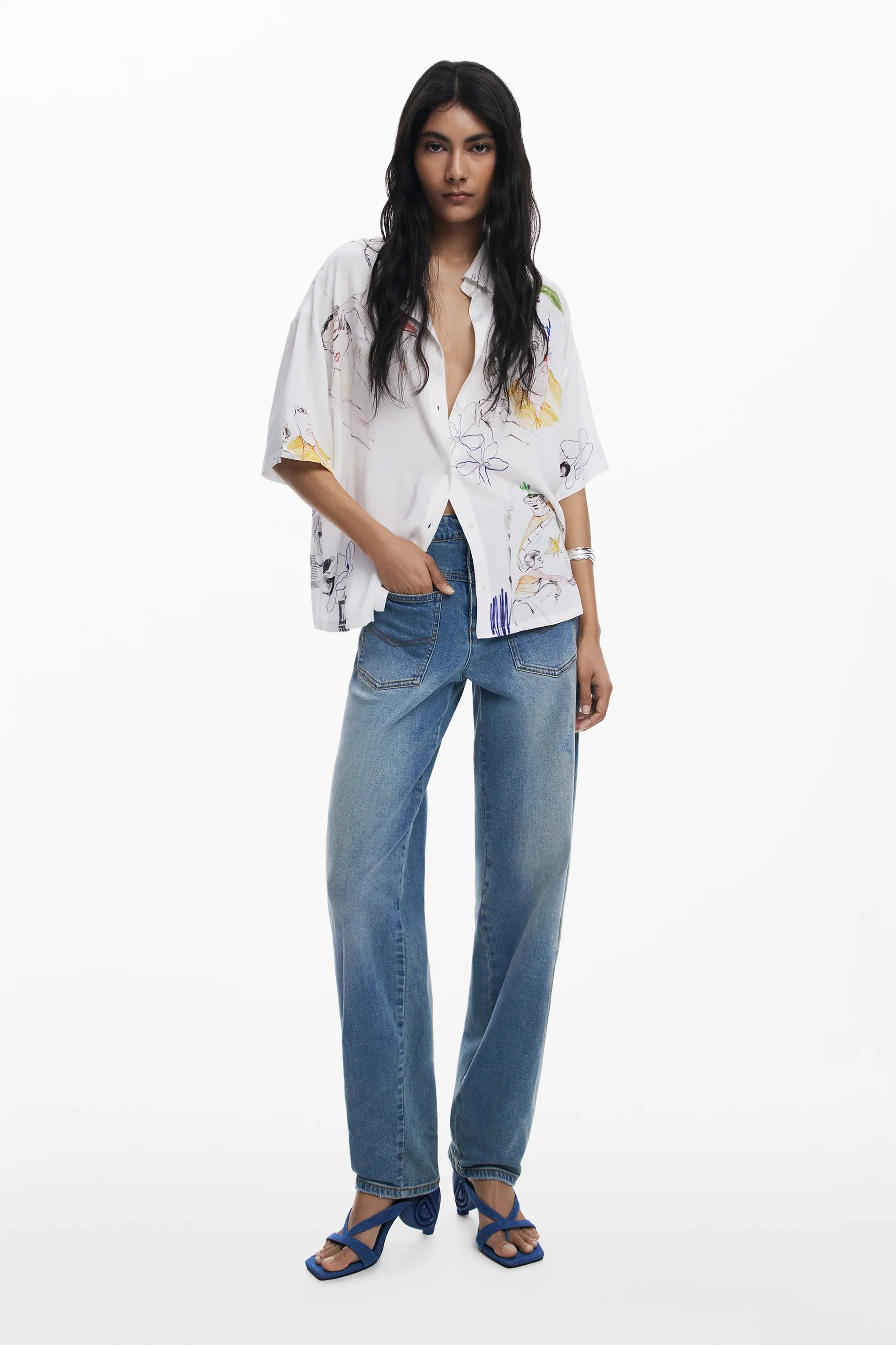 אישה עם חולצה מכופתרת רחבה בהדפס צבעוני, ג'ינס כחול ונעלי עקב כחולות, אופנת CHOZEN