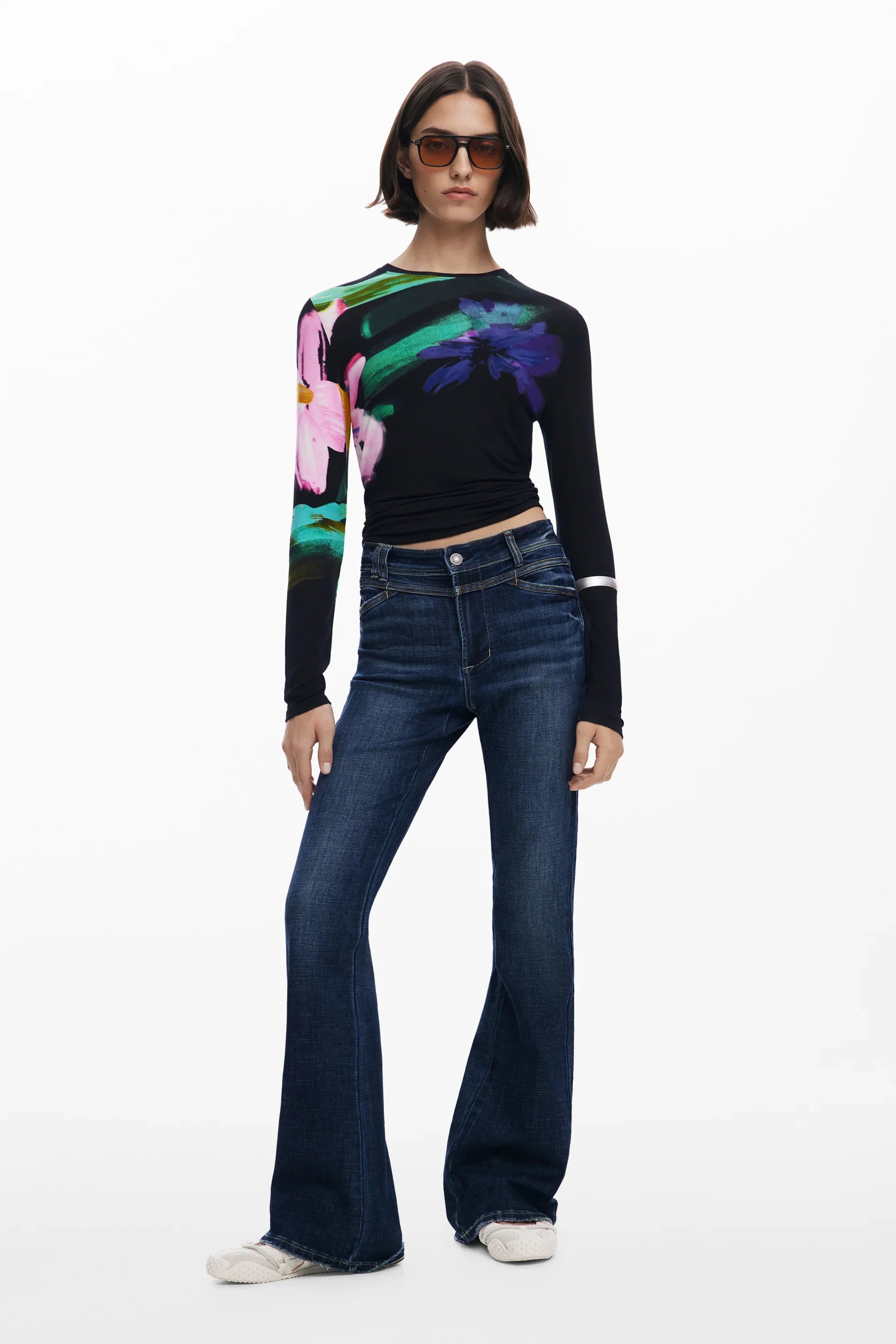 דוגמנית בחולצת שרוול ארוך עם הדפס פרחים צבעוני, ג'ינס כהה ומשקפי שמש, אופנת CHOZEN