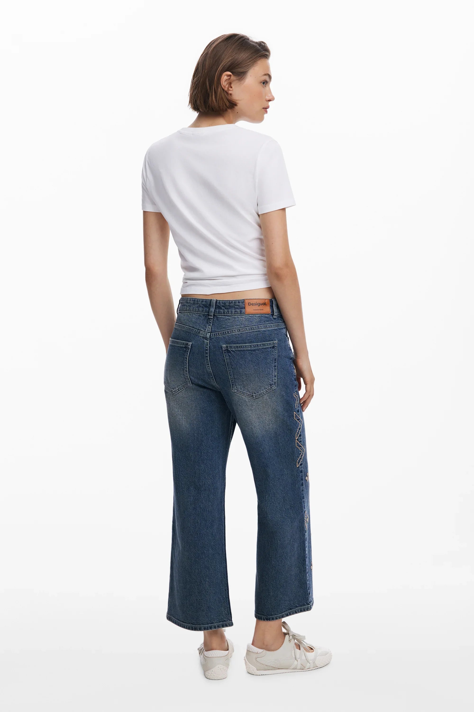 אישה לובשת ג'ינס רחב של Desigual עם חולצה לבנה, צילום אחורי בסטודיו, אופנת נשים CHOZEN