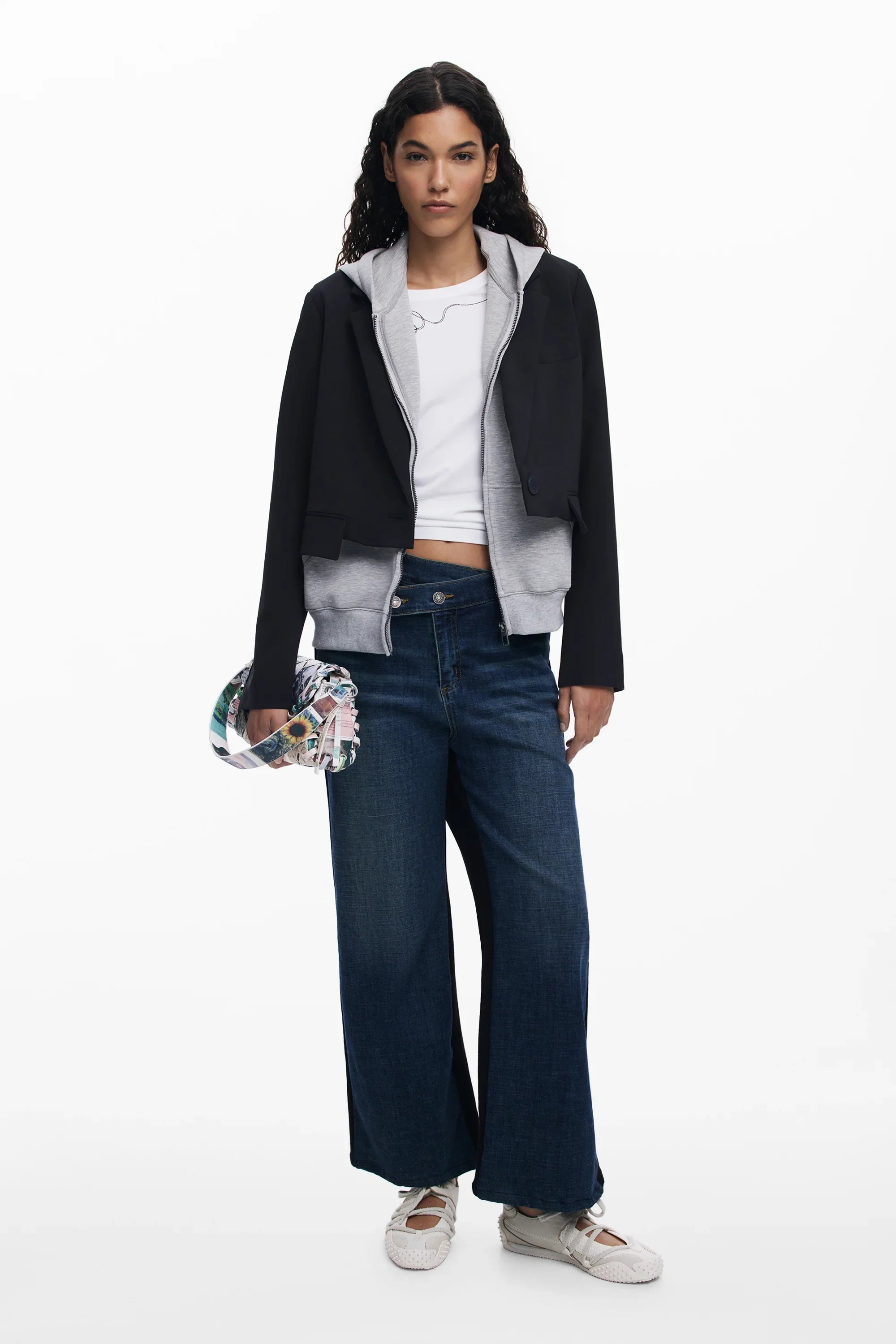 דוגמנית לובשת ג'קט שחור קצר, קפוצ'ון אפור, טי שירט לבנה, מכנסי ג'ינס רחבים ונעלי בד בצילום ל-CHOZEN