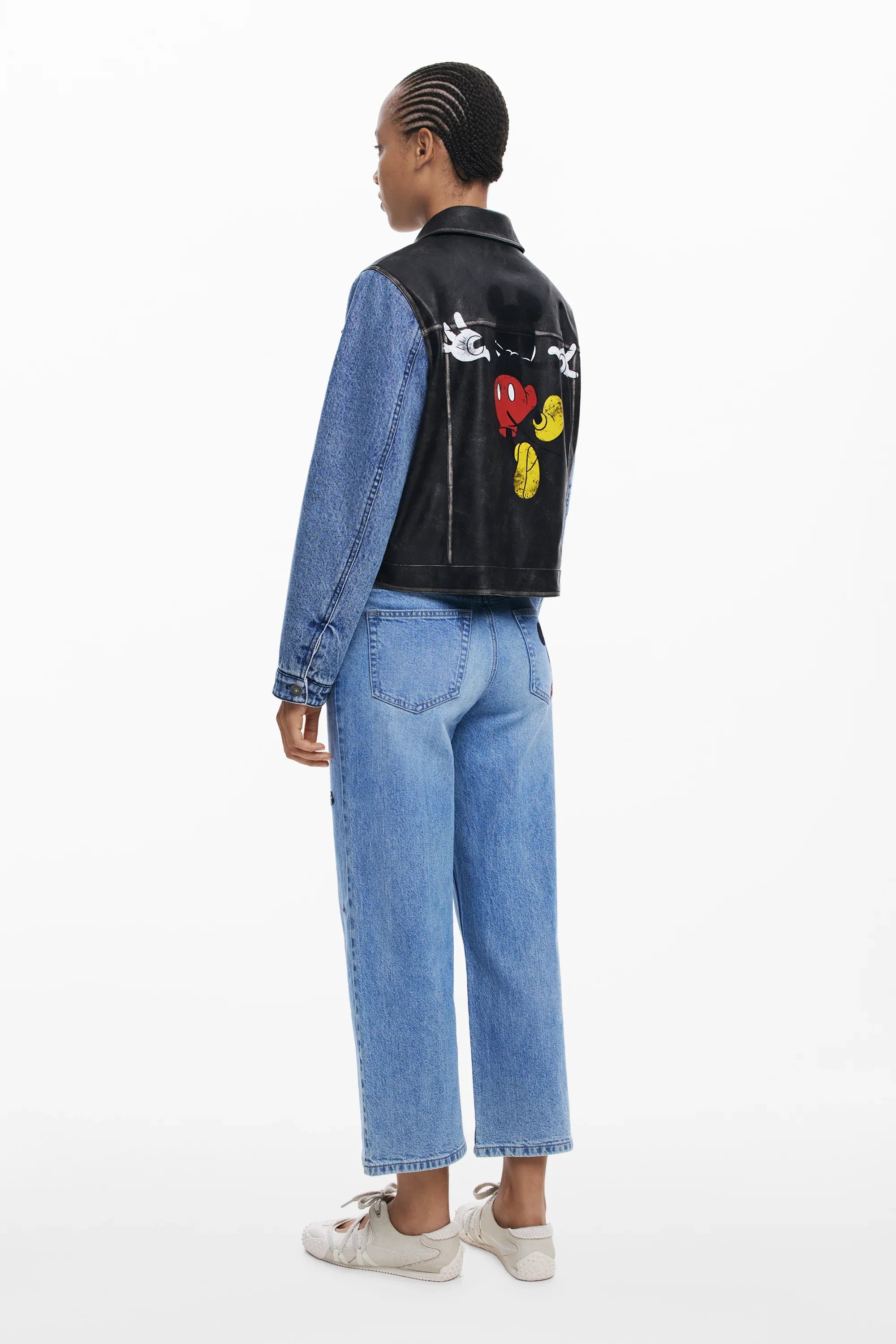 אישה עם ז'קט ג'ינס שחור-כחול בעיצוב מיקי מאוס, ג'ינס ונעליים לבנות, אופנת CHOZEN