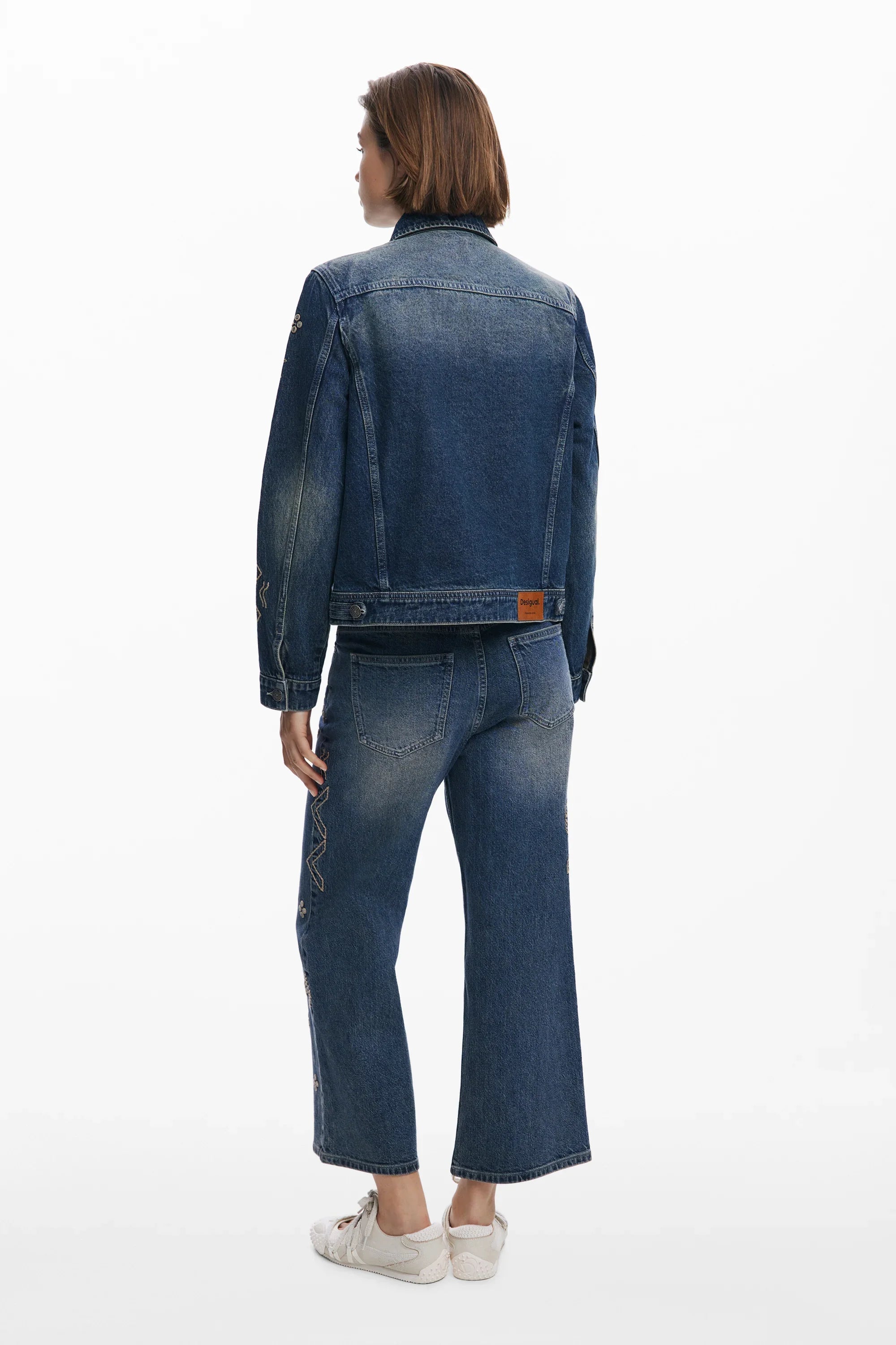 אישה לובשת ז'קט וג'ינס דנים כחולים עם דהייה קלה, מצולמת מאחור, אופנת נשים CHOZEN