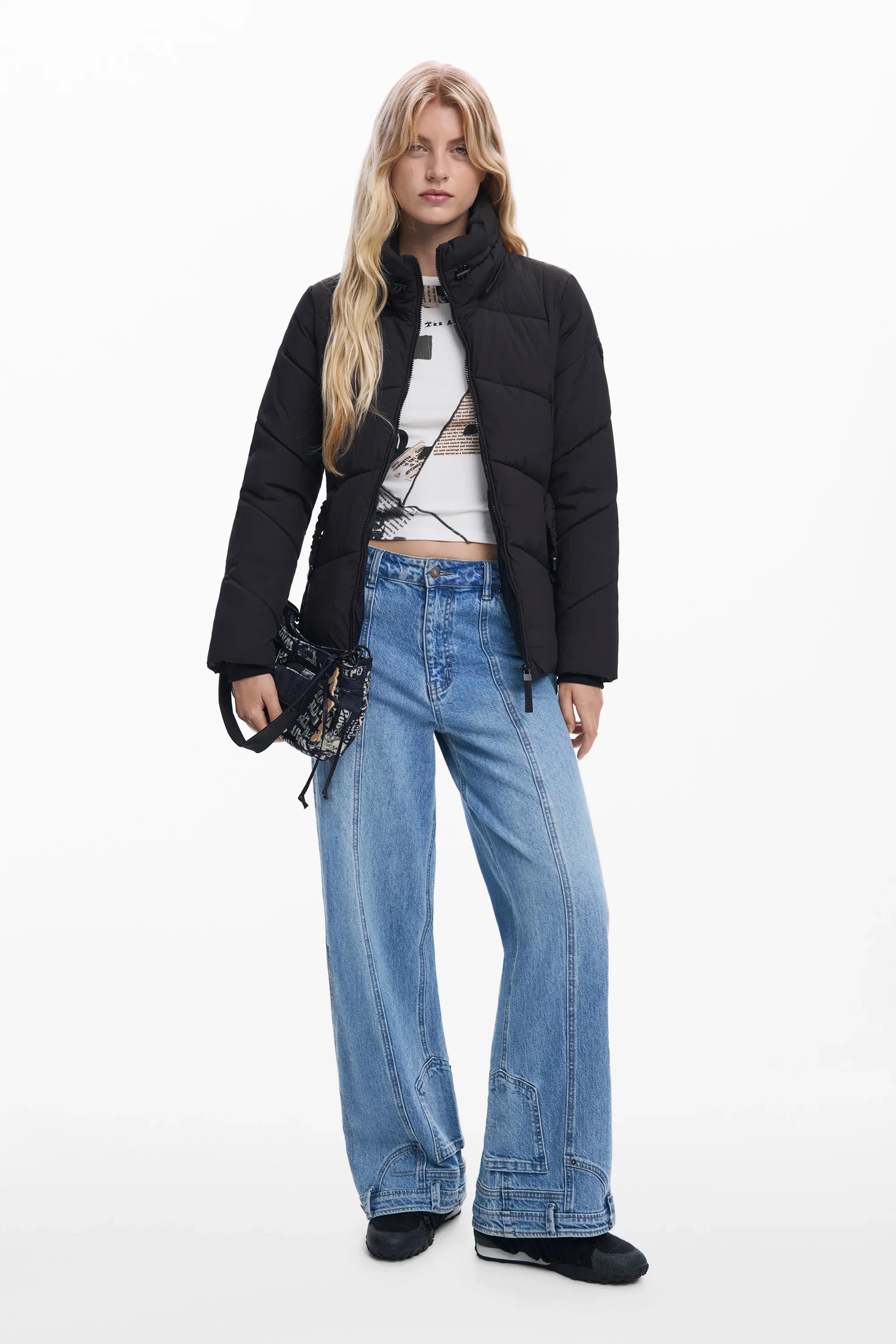 אופנת נשים CHOZEN: דוגמנית במעיל פוך שחור, ג'ינס רחב, טופ לבן ותיק צד, על רקע לבן