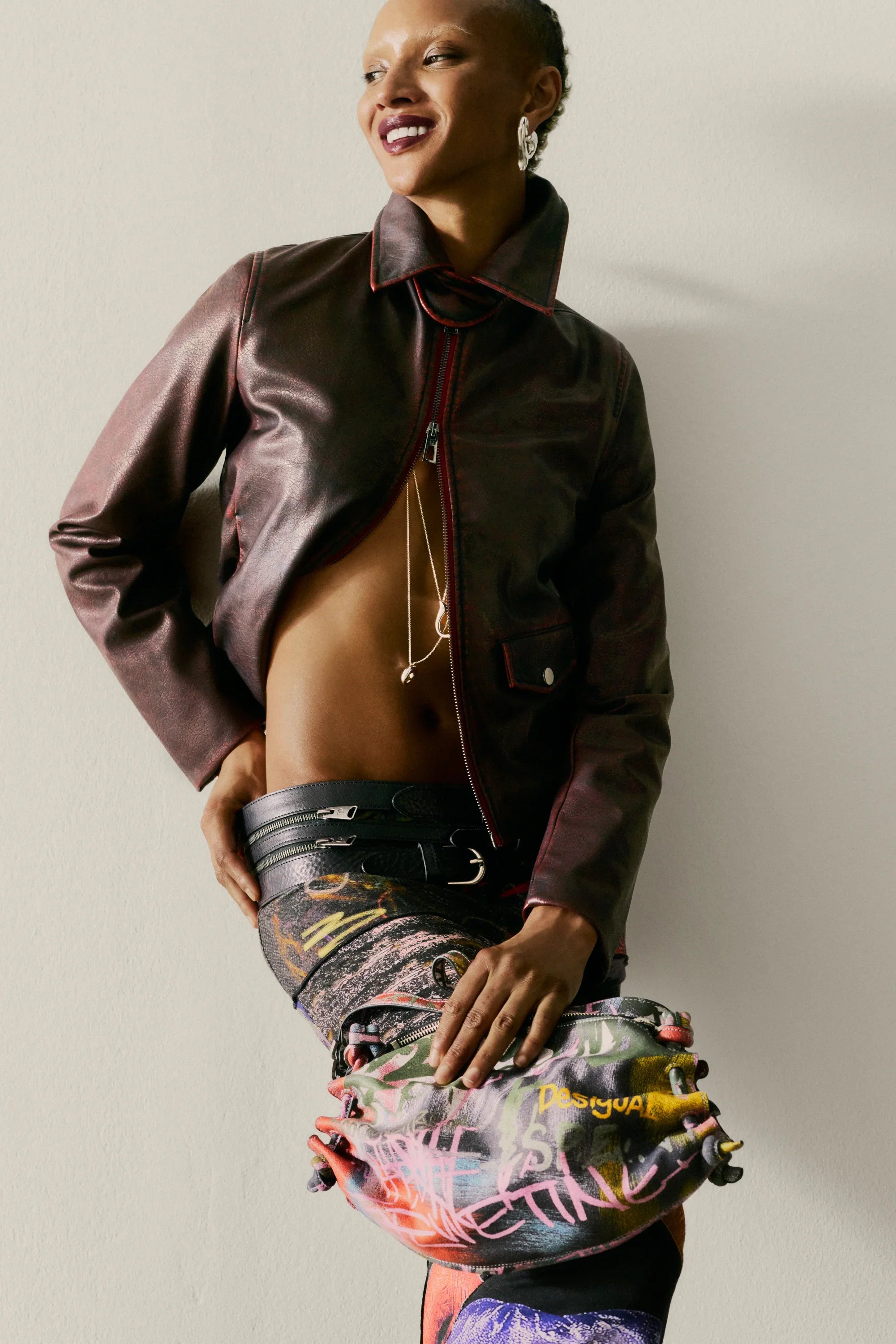 אופנת נשים CHOZEN, דוגמנית עם ז'קט עור חום, מכנסיים מודפסים ותיק Desigual צבעוני