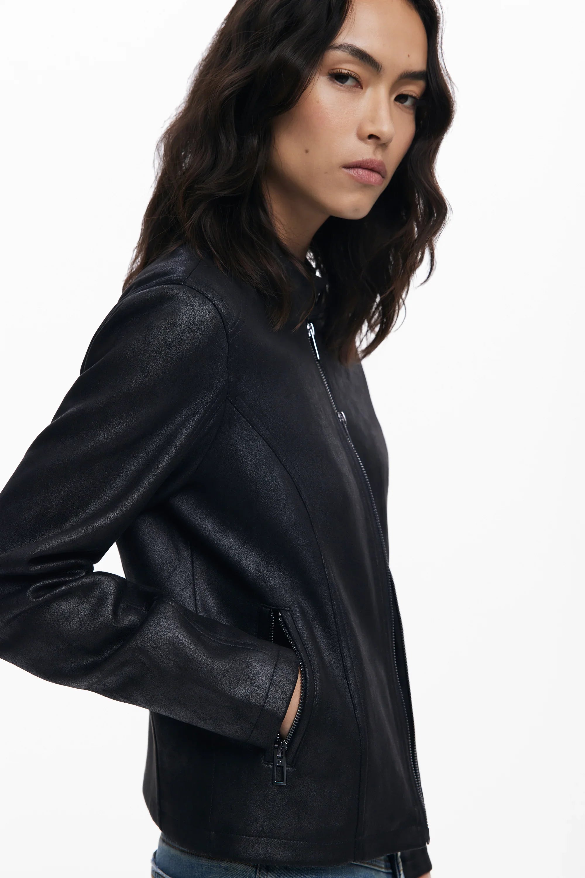 אישה לובשת מעיל עור שחור אופנתי של CHOZEN, צילום בסטודיו על רקע לבן