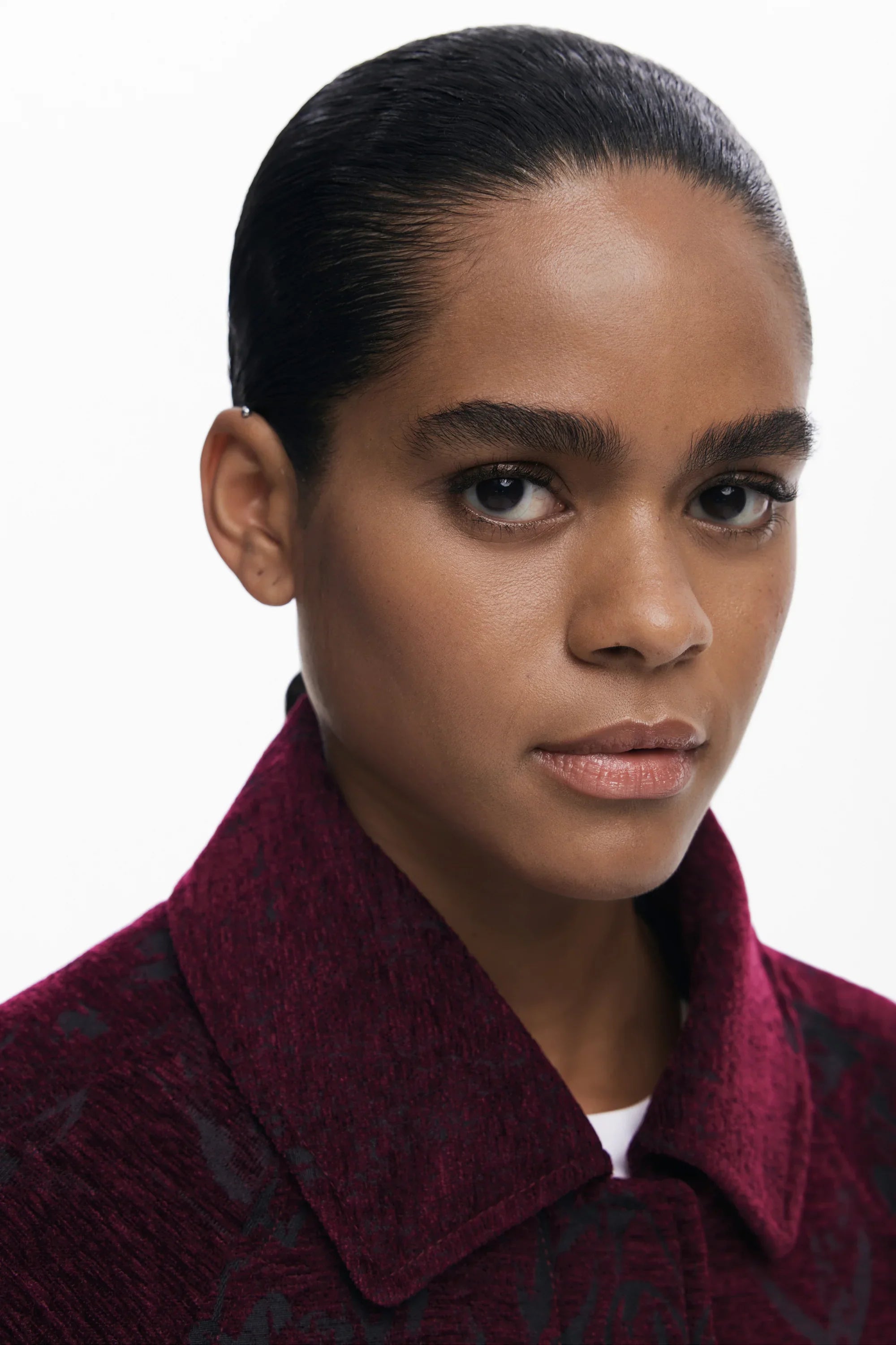 אישה עם שיער אסוף, לובשת מעיל בורדו, צילום סטיילינג לאופנה מבית CHOZEN