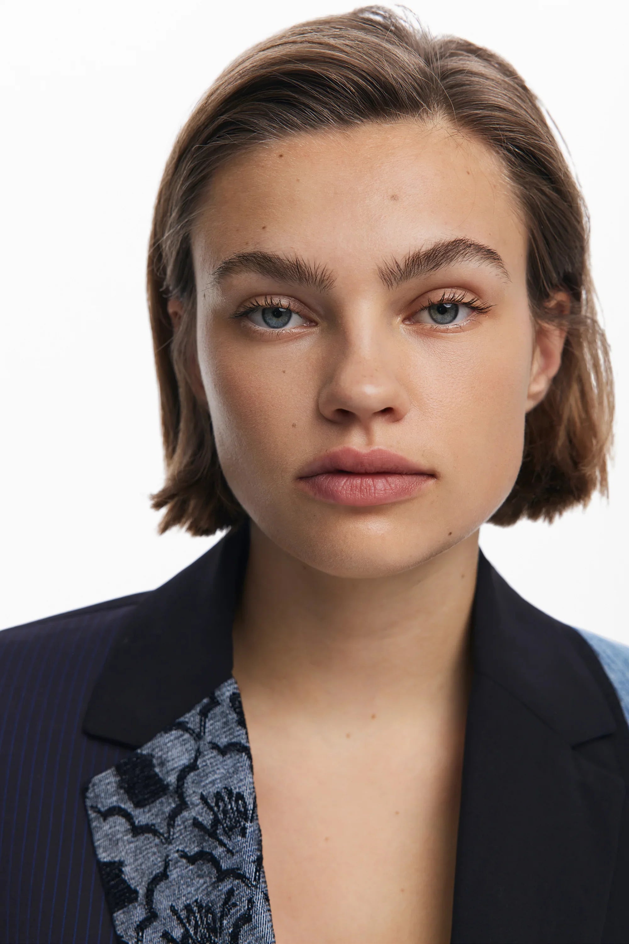 דוגמנית עם שיער קצר ולבוש אופנתי ממותגי CHOZEN על רקע לבן