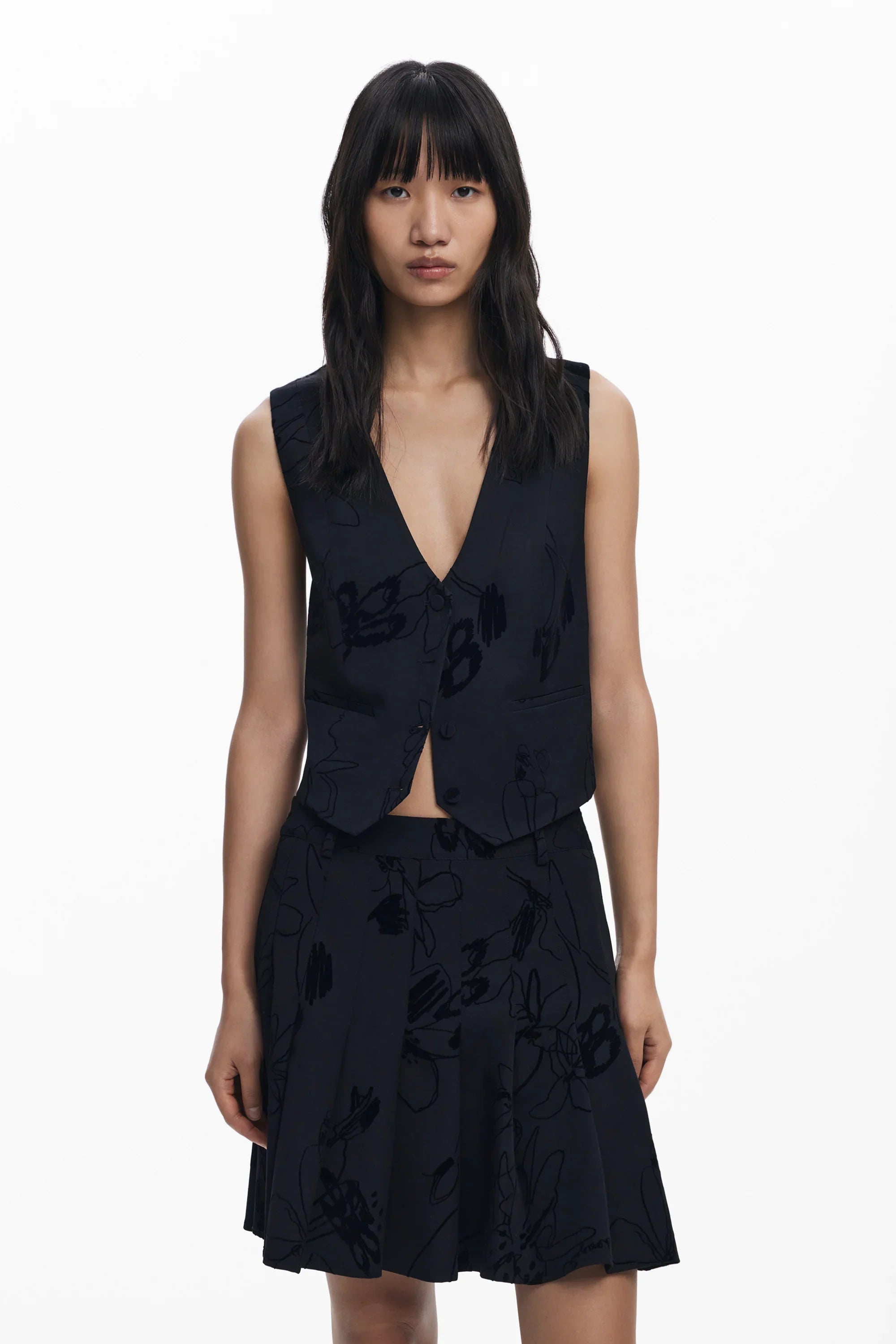 דוגמנית לובשת וסט וחצאית שחורים עם דוגמת פרחים מבית CHOZEN, אופנה מבית קבוצת אלפא