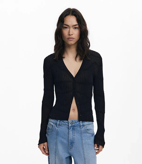 דוגמנית עם קרדיגן שחור מחורץ וג׳ינס בהיר מציגה אופנת נשים עדכנית באתר CHOZEN