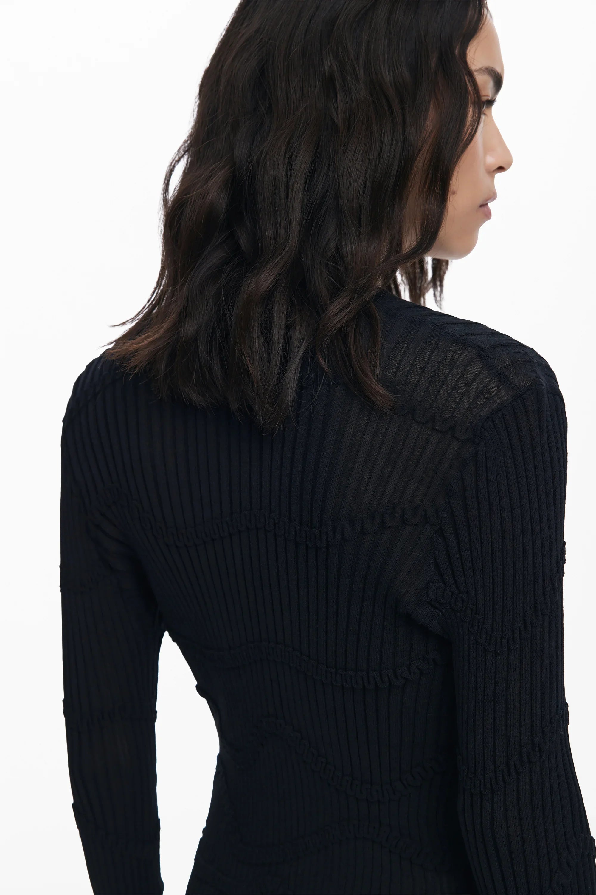 אישה לבושה בסוודר שחור מחויט ומחורץ, צילום גב, CHOZEN, אופנה לנשים