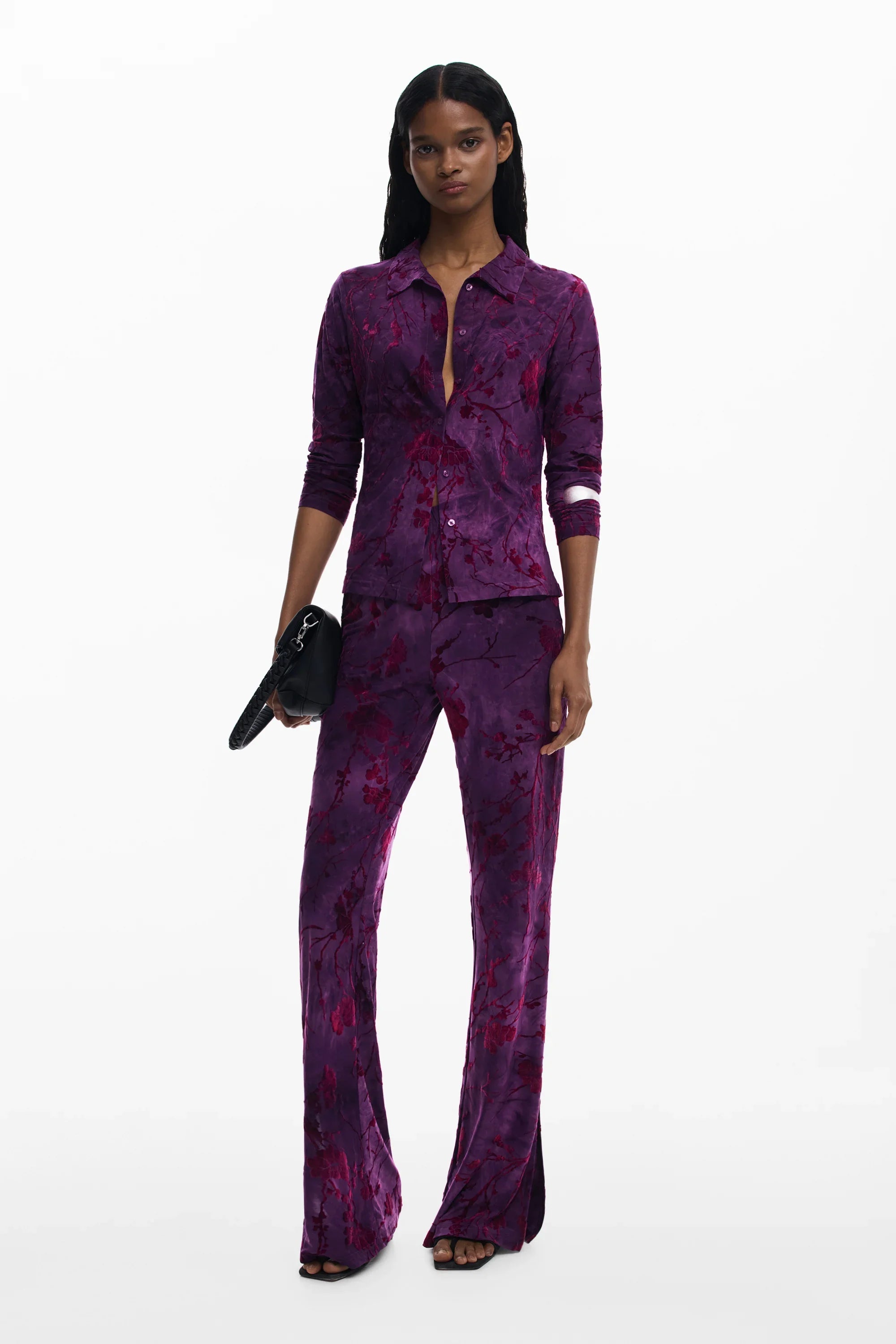 דוגמנית לובשת חליפת קטיפה סגולה עם הדפס פרחוני, מחזיקה תיק שחור, אופנת נשים CHOZEN