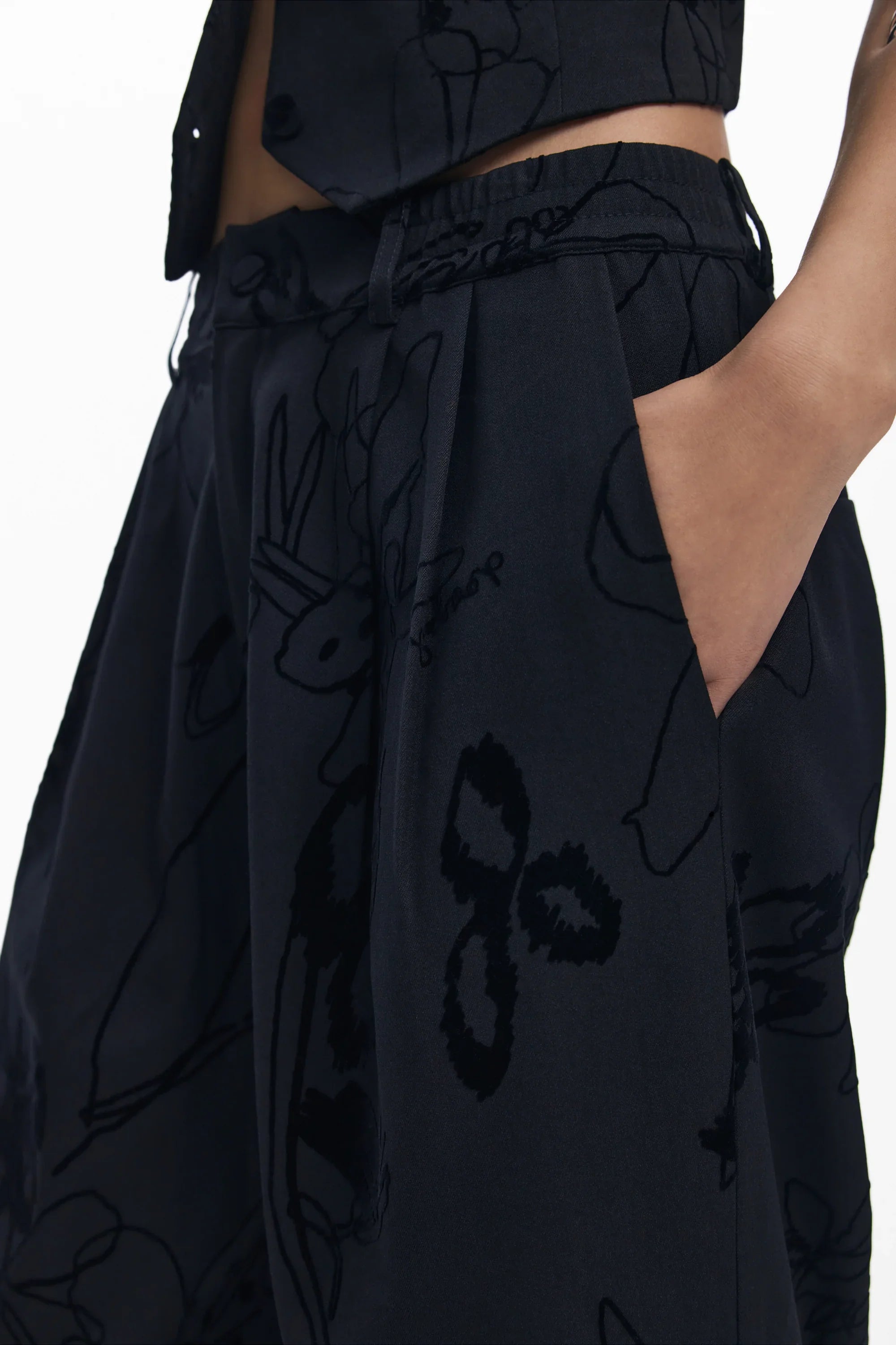 מכנסיים רחבים שחורים עם הדפס אומנותי, מותג אופנה CHOZEN, תקריב על כיס