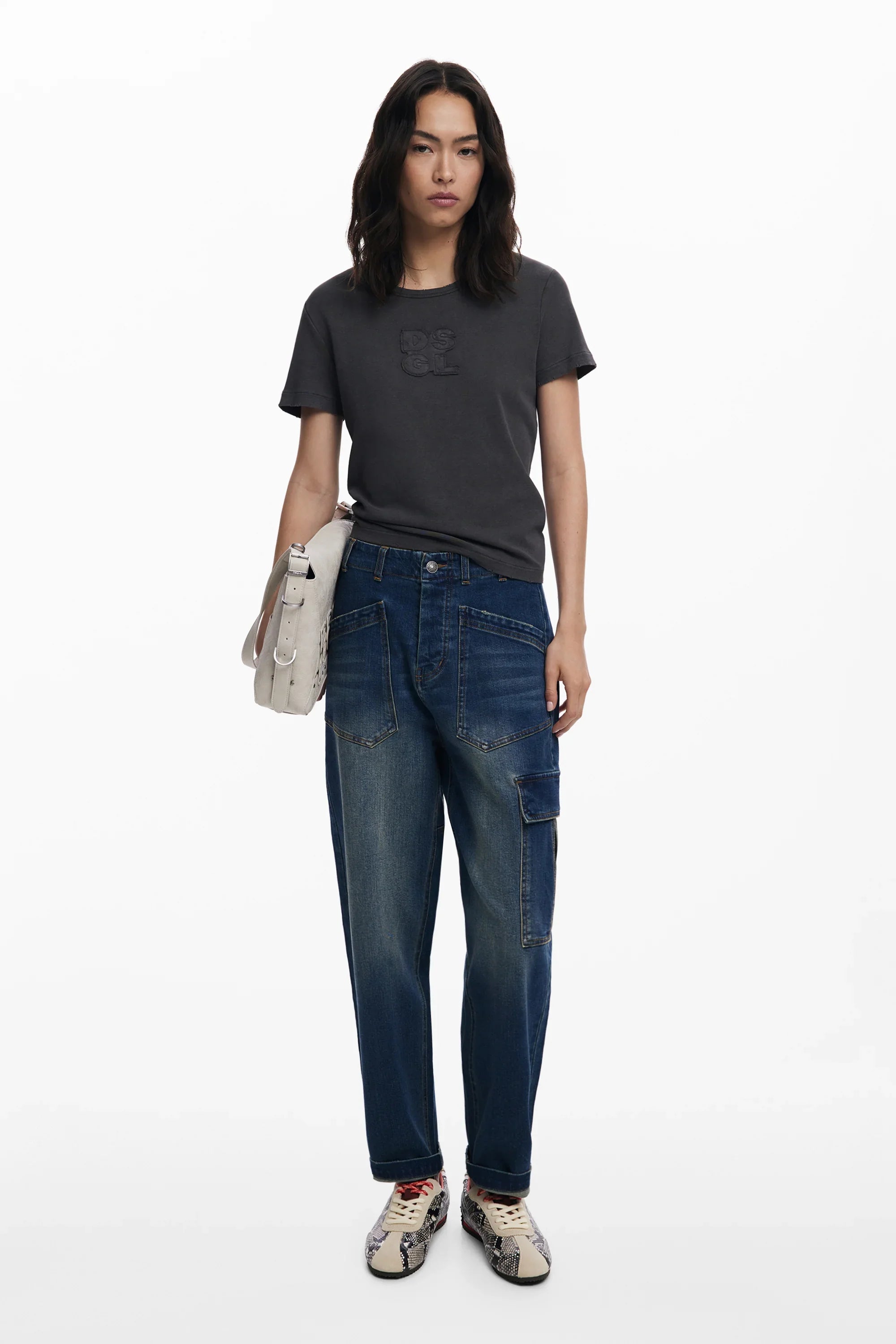 אישה עם חולצת DSGL שחורה, ג'ינס כחול ומוקסינים, מתוך קולקציית אופנה באתר CHOZEN