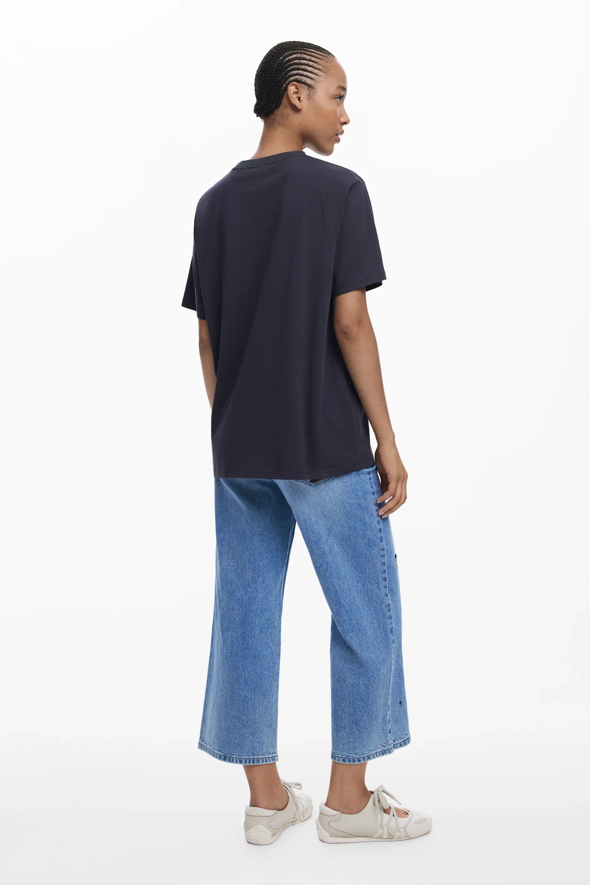 אופנת נשים CHOZEN, דוגמנית בלבוש קז'ואל: חולצה שחורה קצרה, ג'ינס ישר ונעלי ספורט לבנות