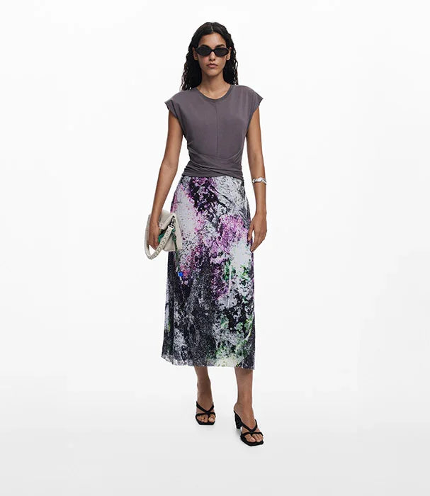 אישה עם חולצה אפורה וחצאית מידי מודפסת צבעונית, משקפי שמש, תיק אלגנטי, אופנה CHOZEN