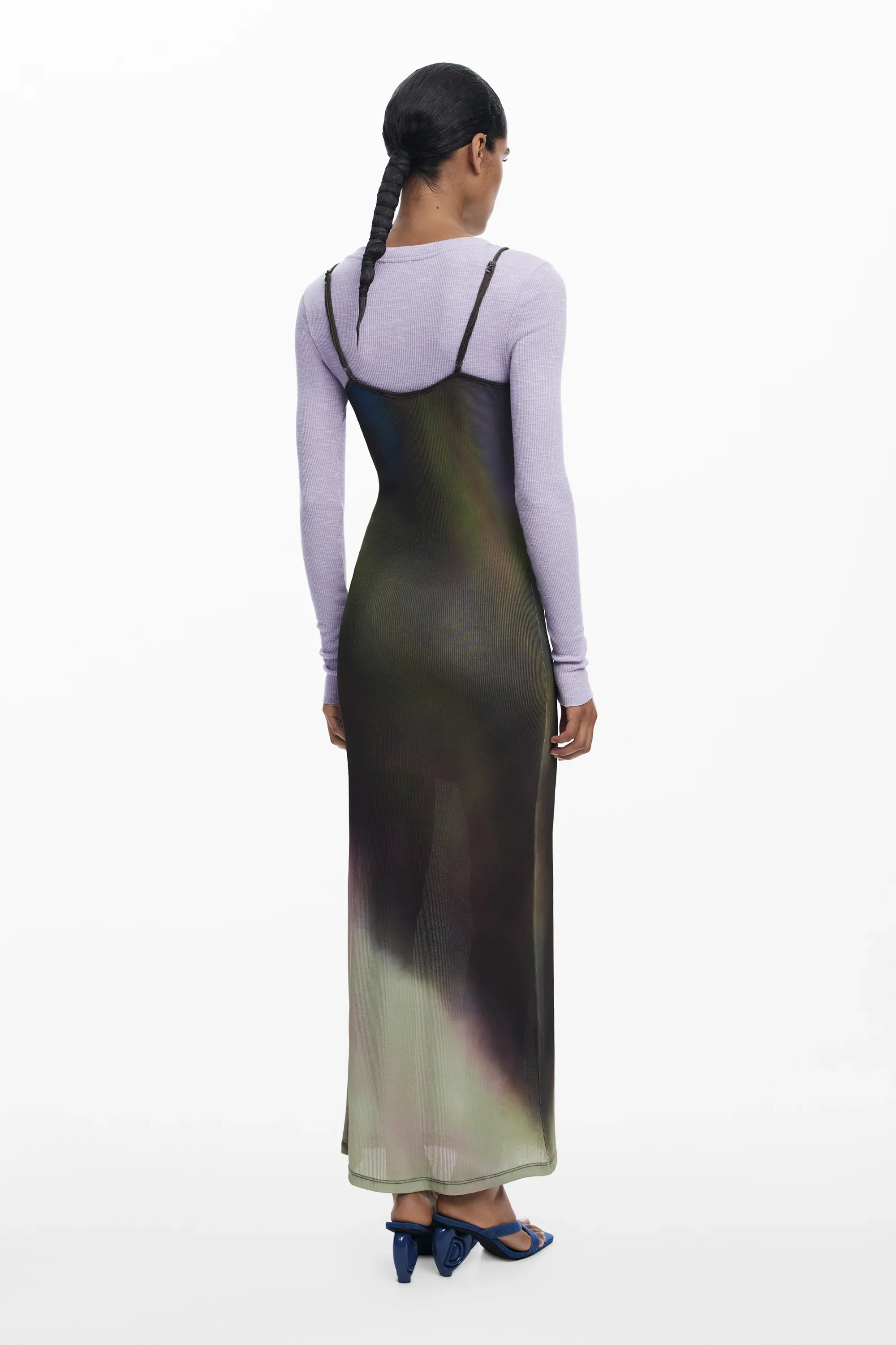 אישה עם שמלה ארוכה בצבעים מטושטשים מעל חולצה סגולה, נעלי עקב כחולות, על רקע לבן. CHOZEN