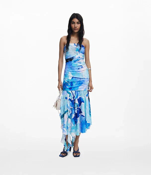 דוגמנית בשמלת קיץ כחולה עם דוגמת מים לאסימטרית, נעלי עקב כחולות ותיק קטן, CHOZEN