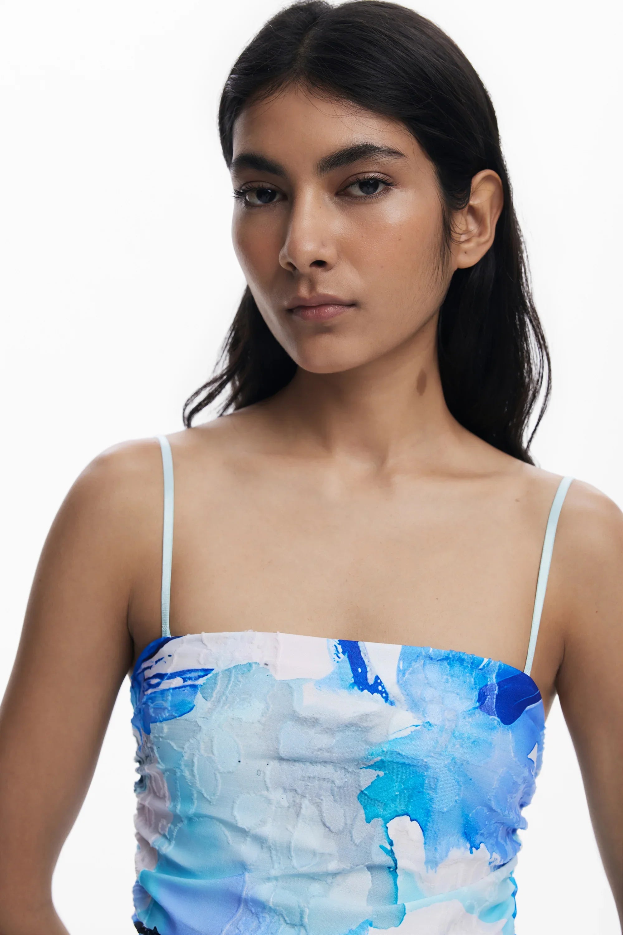 אישה עם שיער כהה לובשת גופיית קיץ דקה בהדפס צבעי מים כחול ולבן על רקע לבן, CHOZEN מותגים מובילים