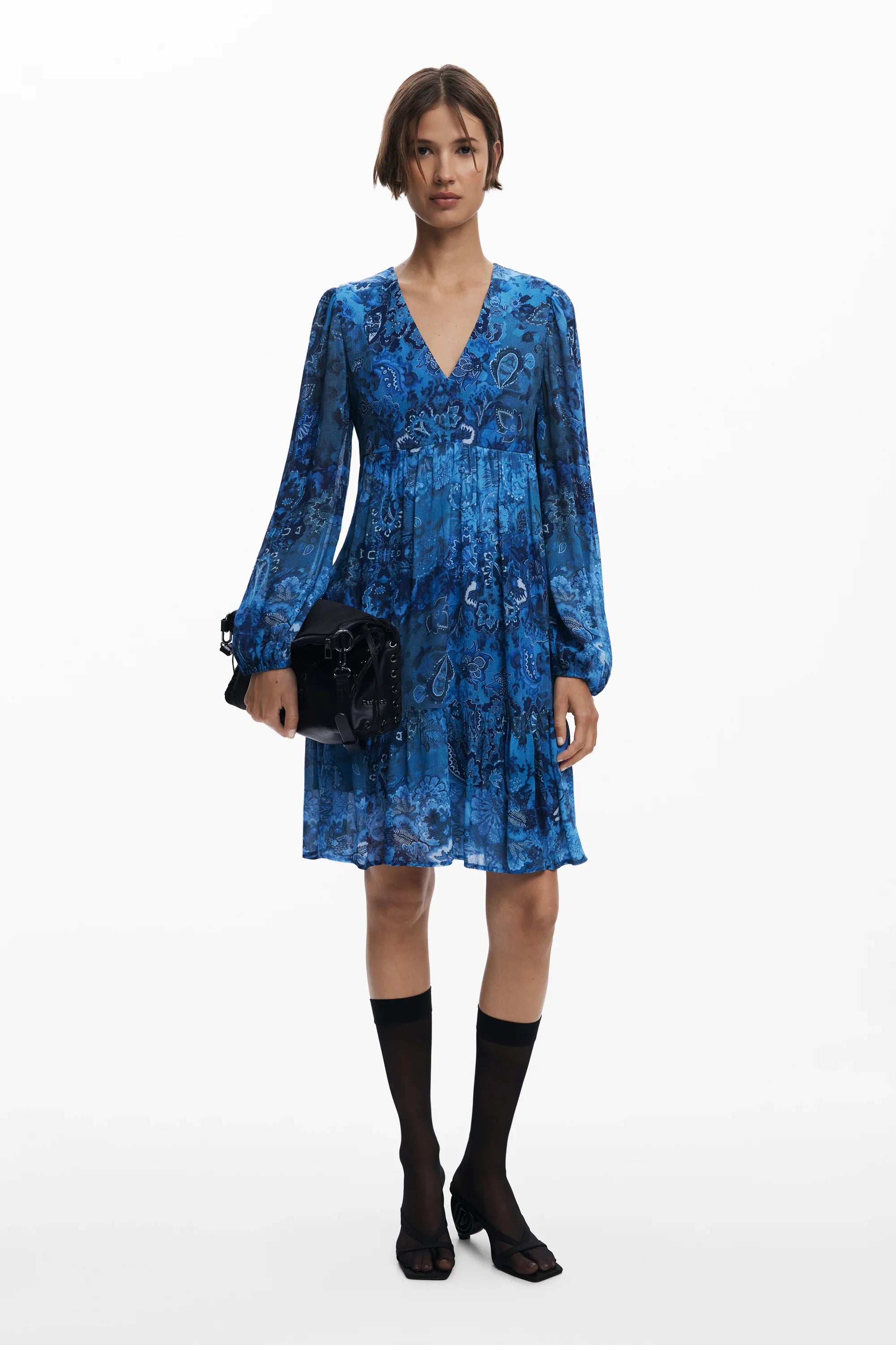 דוגמנית לובשת שמלת מיני כחולה בהדפס פרחוני עם שרוולים ארוכים, נעליים שחורות ותיק יד, CHOZEN