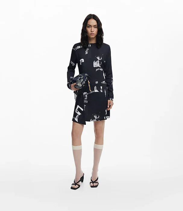 דוגמנית לובשת שמלת מיני שחורה עם הדפסים לבנים, מחזיקה תיק אופנה, צילום לאתר CHOZEN