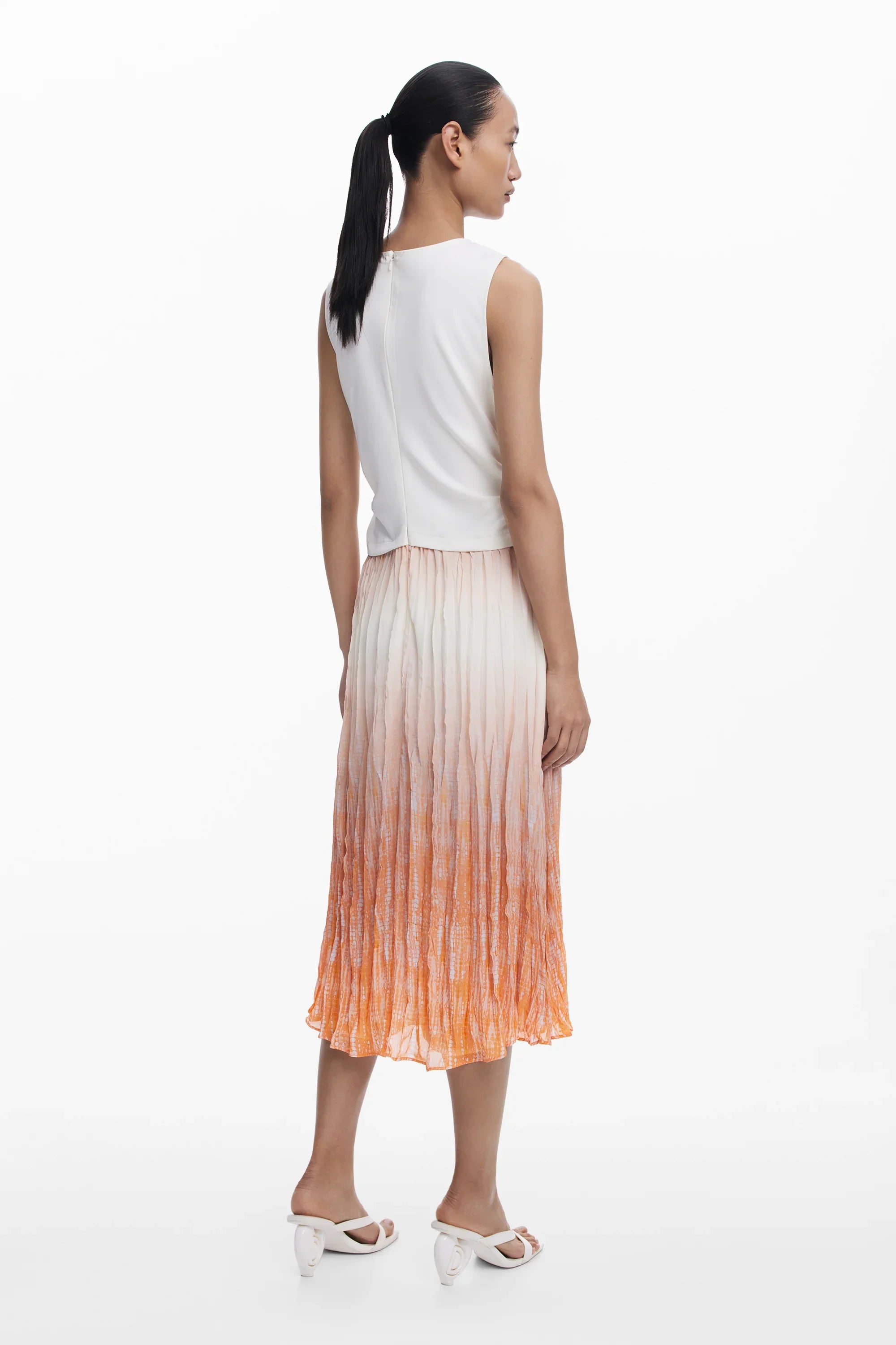 אישה בשמלת קיץ לבנה עם חצאית פליסה בצבע כתום דהוי, צילום אופנה ל-CHOZEN