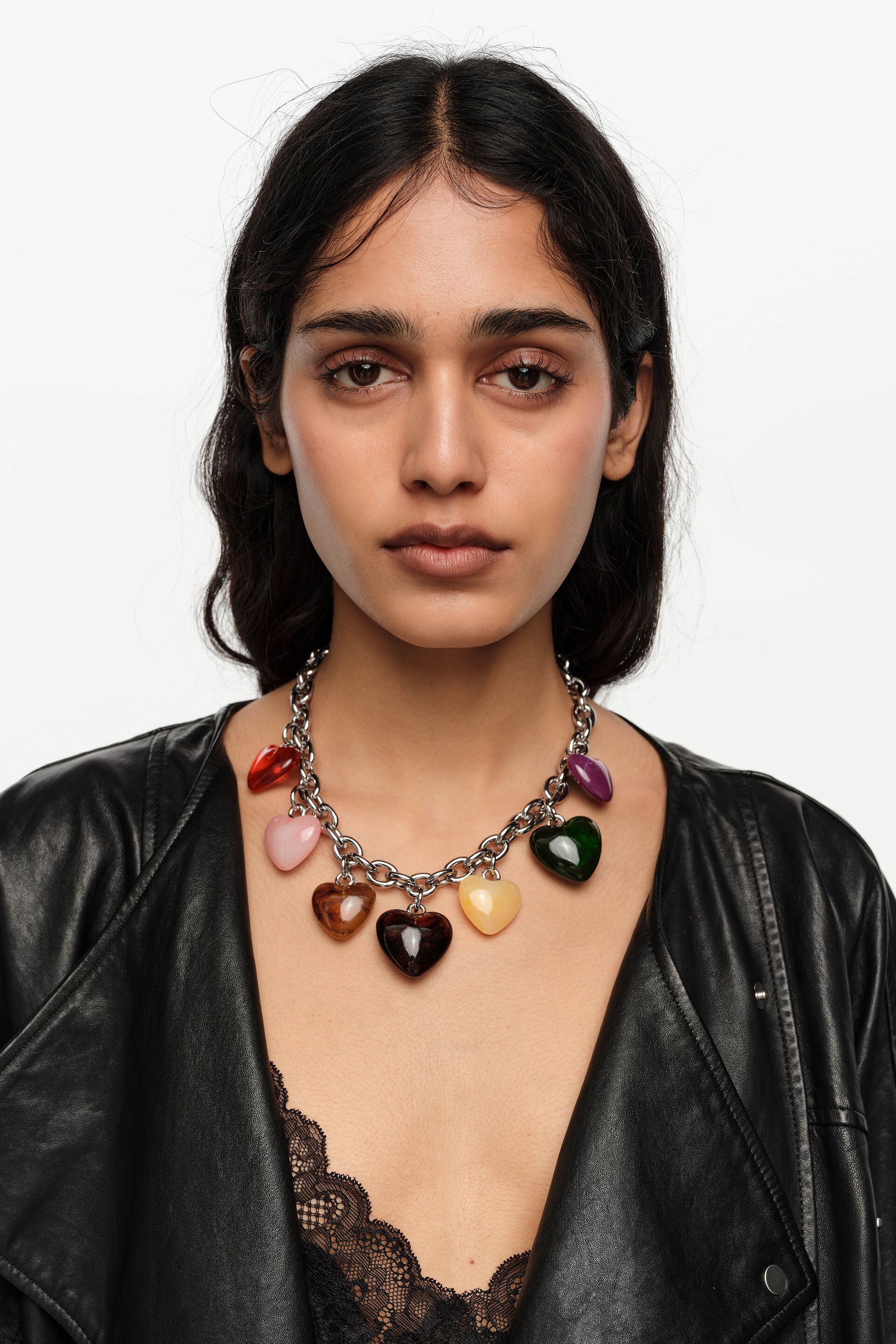 דוגמנית עם שרשרת גורמט כסף ותליוני לב צבעוניים, לוק אופנתי, ג'קט עור