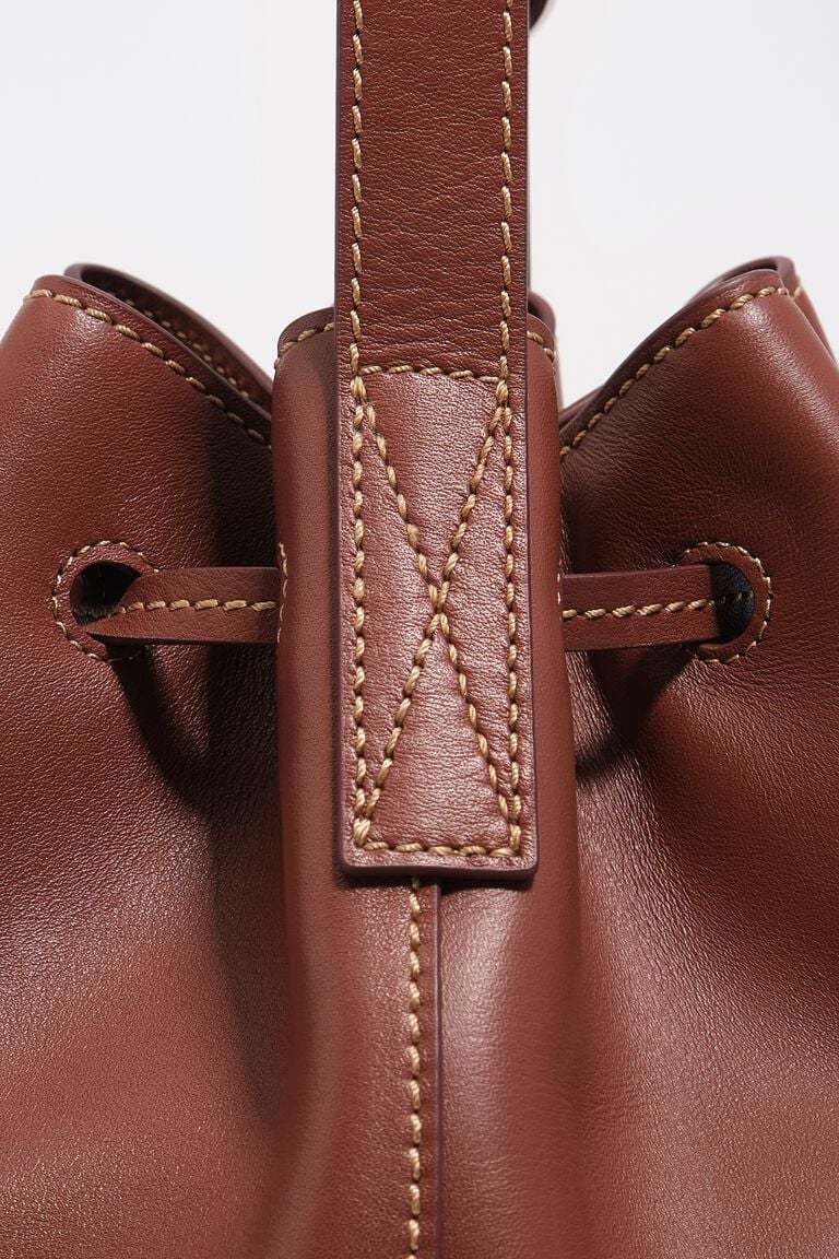 תקריב על תיק עור חום עם תפרים בולטים וסגנון יוקרתי, תיק אופנה לנשים