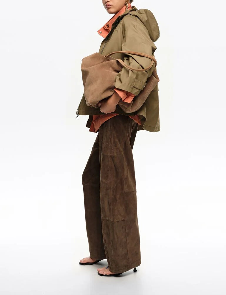 אישה לובשת מכנסי זמש חומים רחבים, ג'קט ירוק תיק קז'ואל חום ונעלי עקב פתוחות