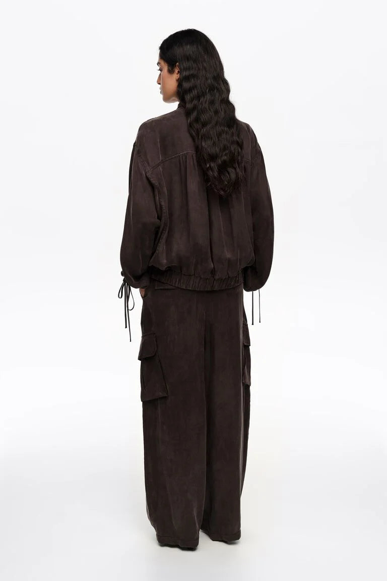 אישה לובשת סט בגדים כהה עם מכנסי קארגו רחבים ומעיל תואם, צילום גב על רקע לבן