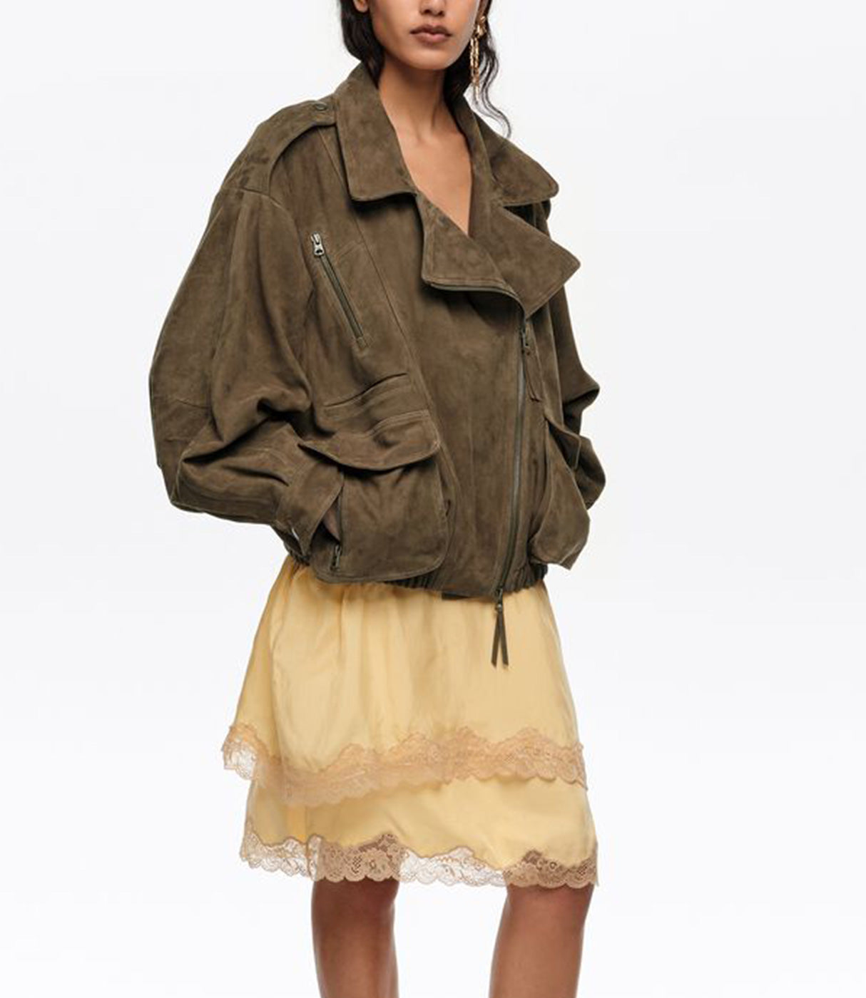 אישה עם ז'קט סוויד חאקי בגזרה רחבה וחצאית תחרה צהובה אופנתית