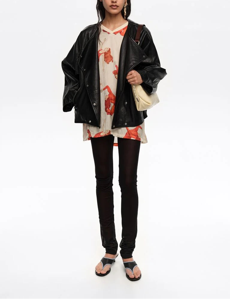 אישה עם ג'קט עור שחור, טוניקה בהדפס אדום, טייץ שחור וסנדלים אופנתיים