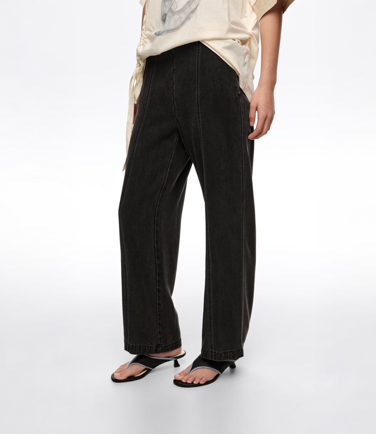 מכנסי ג'ינס שחור רחבים לנשים, סטייל אופנתי עם תפרים דקורטיביים, מצולם על דוגמנית עם חולצה בהירה וסנדלים.