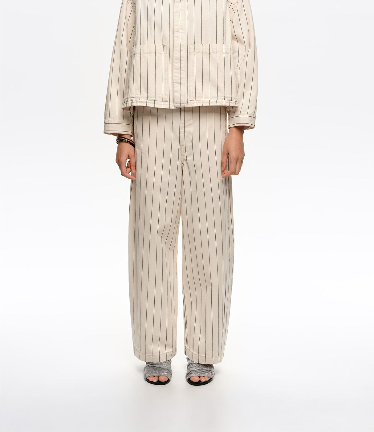 חליפת נשים בצבע בז' עם פסים אנכיים, מכנסיים רחבים וסנדלים אפורים