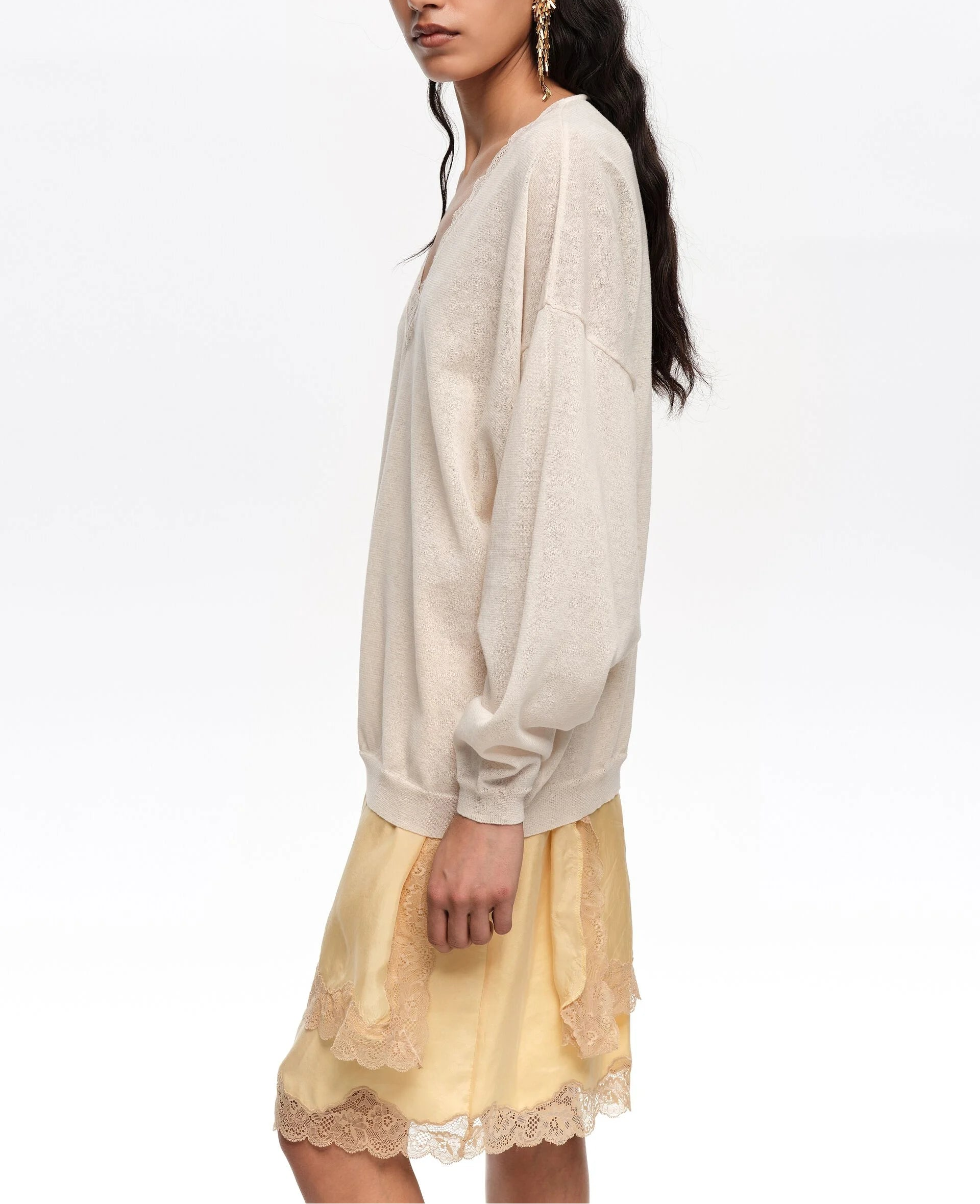 אישה לובשת סוודר בז' חופשי וחצאית צהובה עם תחרה, אופנה נשית אלגנטית