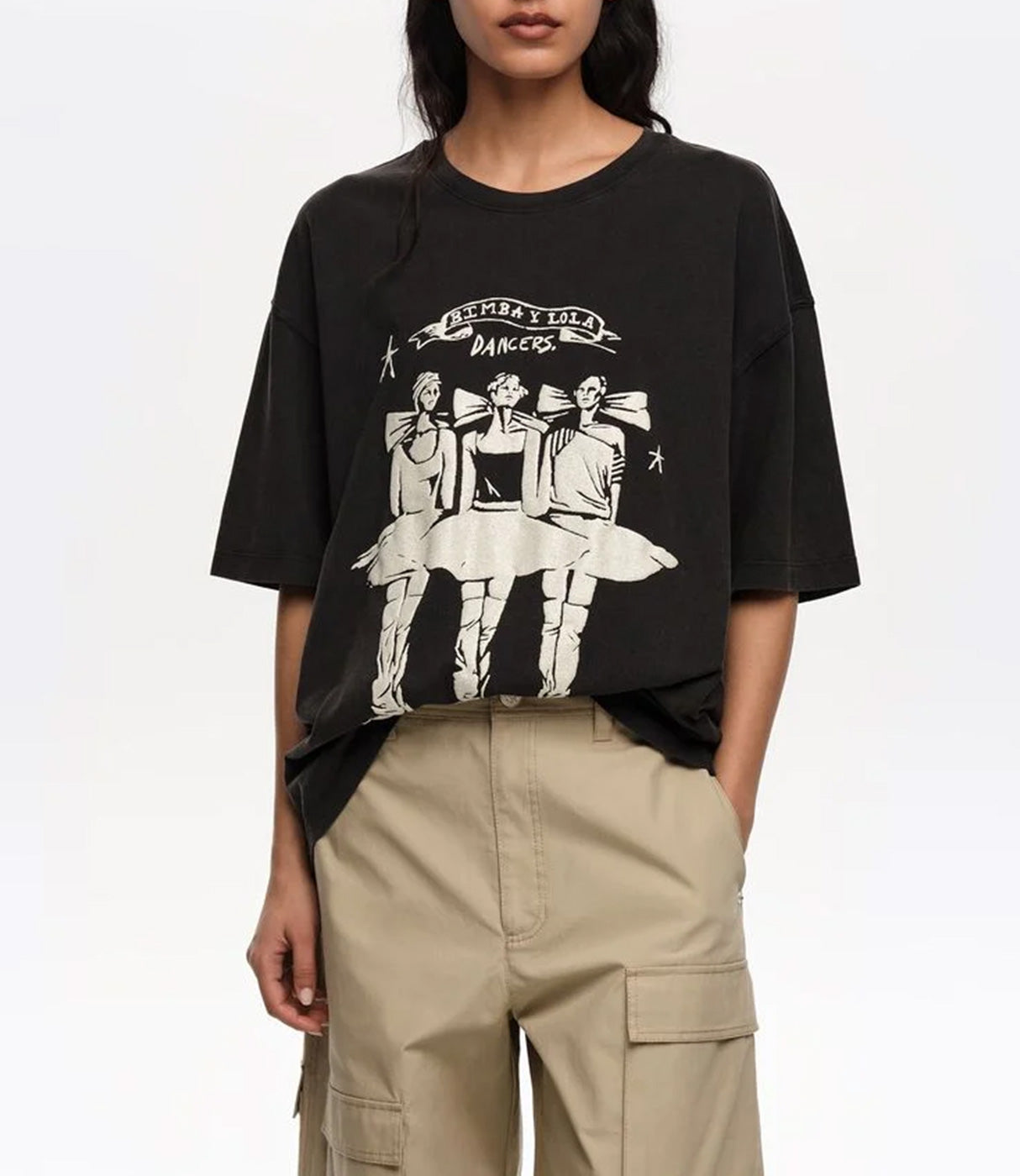 חולצת טי שחורה עם הדפס רקדניות וכיתוב, לבוש עם מכנסי בז' קז'ואל