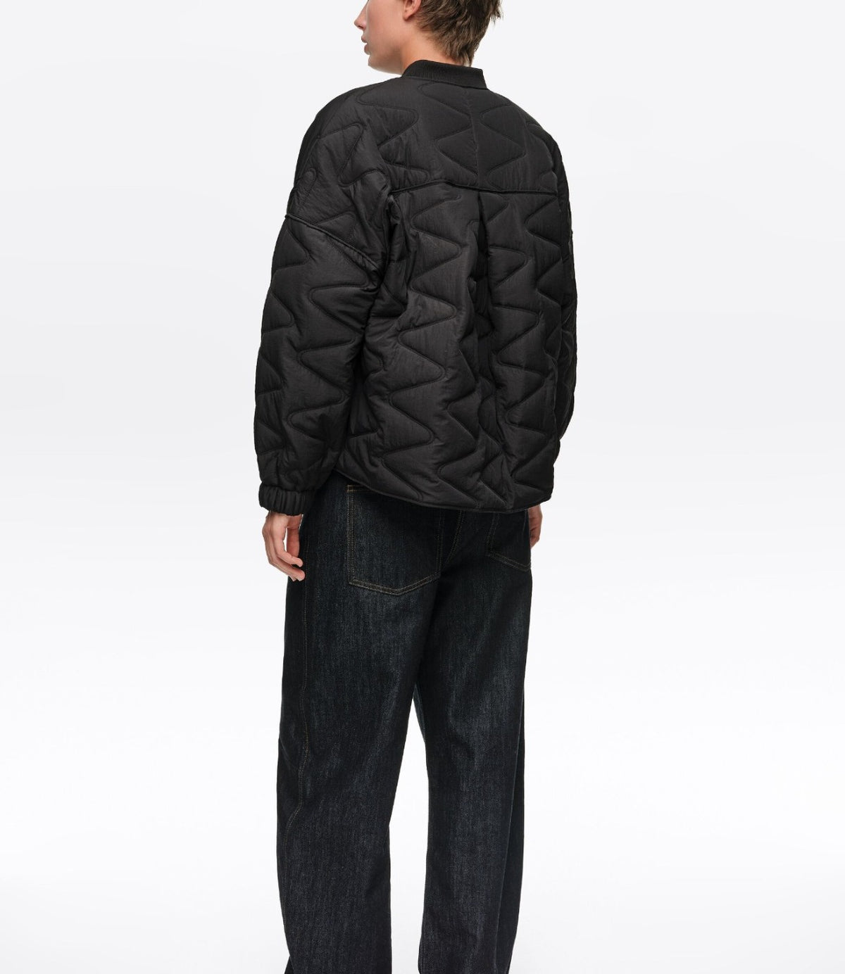 דוגמן ממבט אחורי לובש מעיל פוך קצר בצבע שחור עם תפרי פסים גאומטריים - CHOZEN