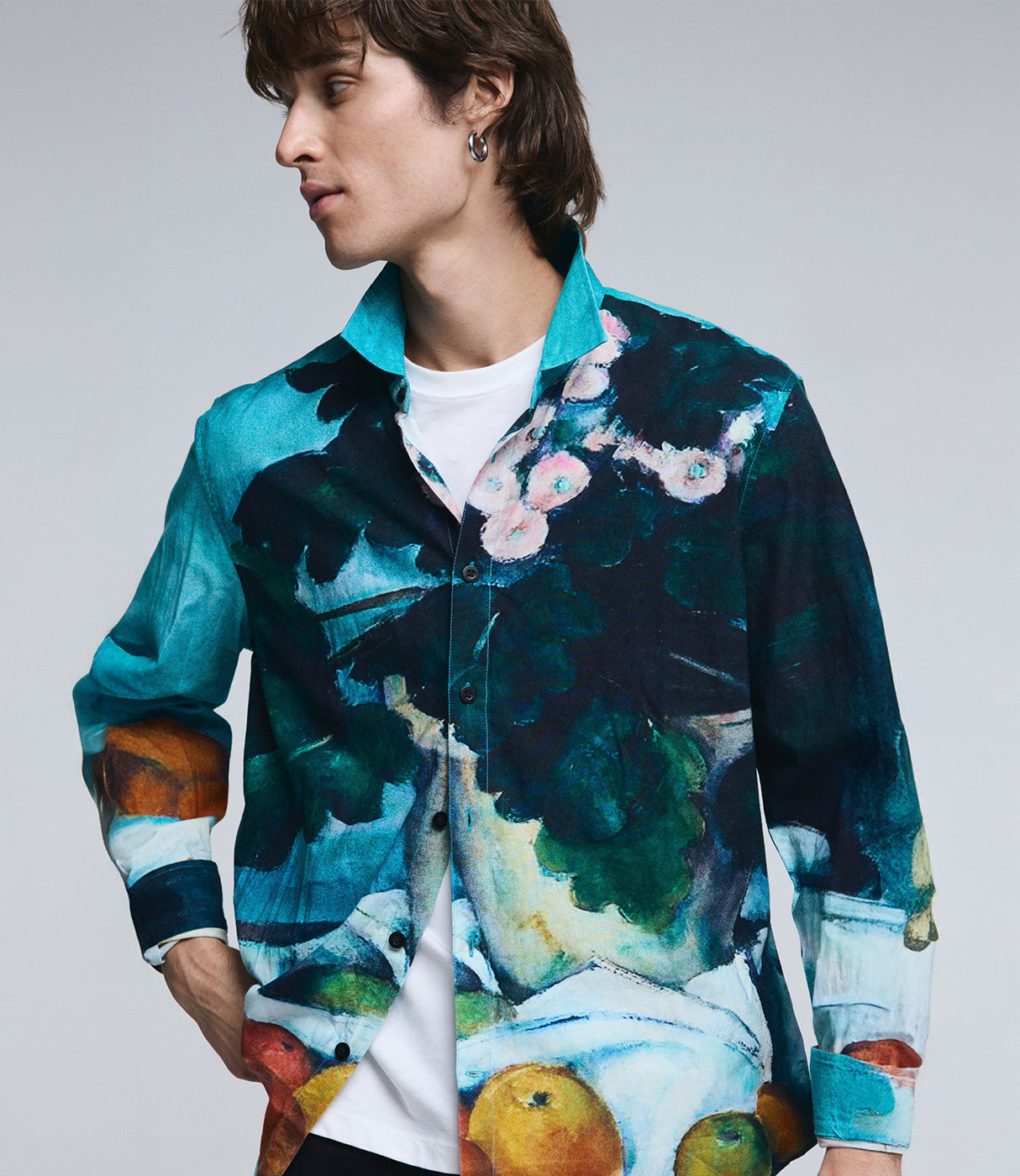 גבר לובש חולצה מכופתרת עם הדפס צבעוני בסגנון אמנותי, רקע אחיד