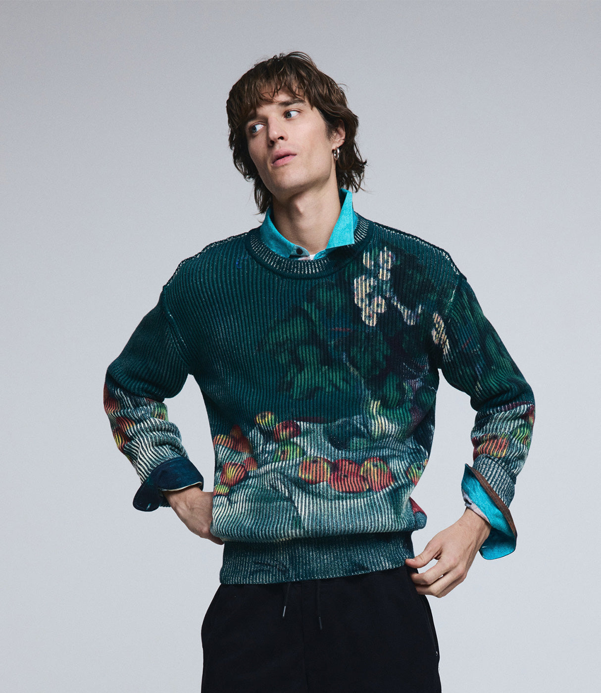 דוגמן לובש סוודר גברי עם הדפס פירות צבעוני על רקע פשוט, אופנת גברים טרנדית