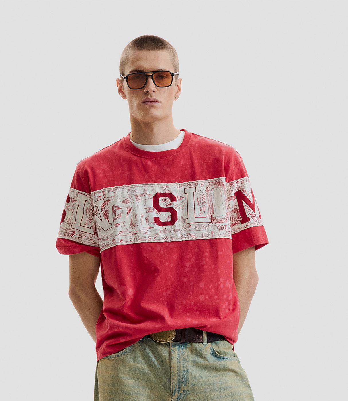 גבר עם חולצת טי אדומה מודפסת, גזרה רחבה, משקפי שמש, רקע לבן