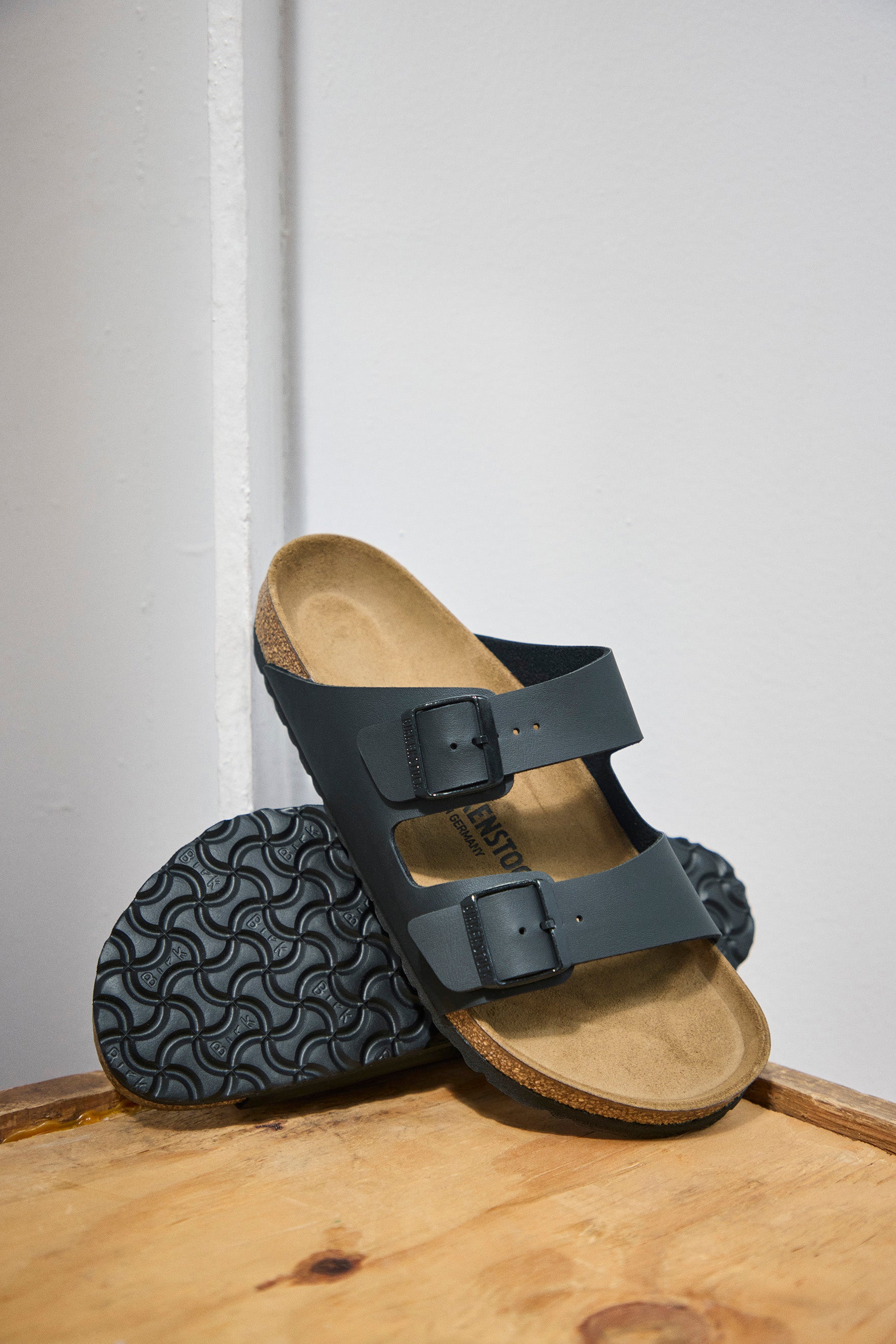 סנדלי בירקנשטוק שחורים כפולים על משטח עץ, נעלי נוחות אופנתיות באתר CHOZEN