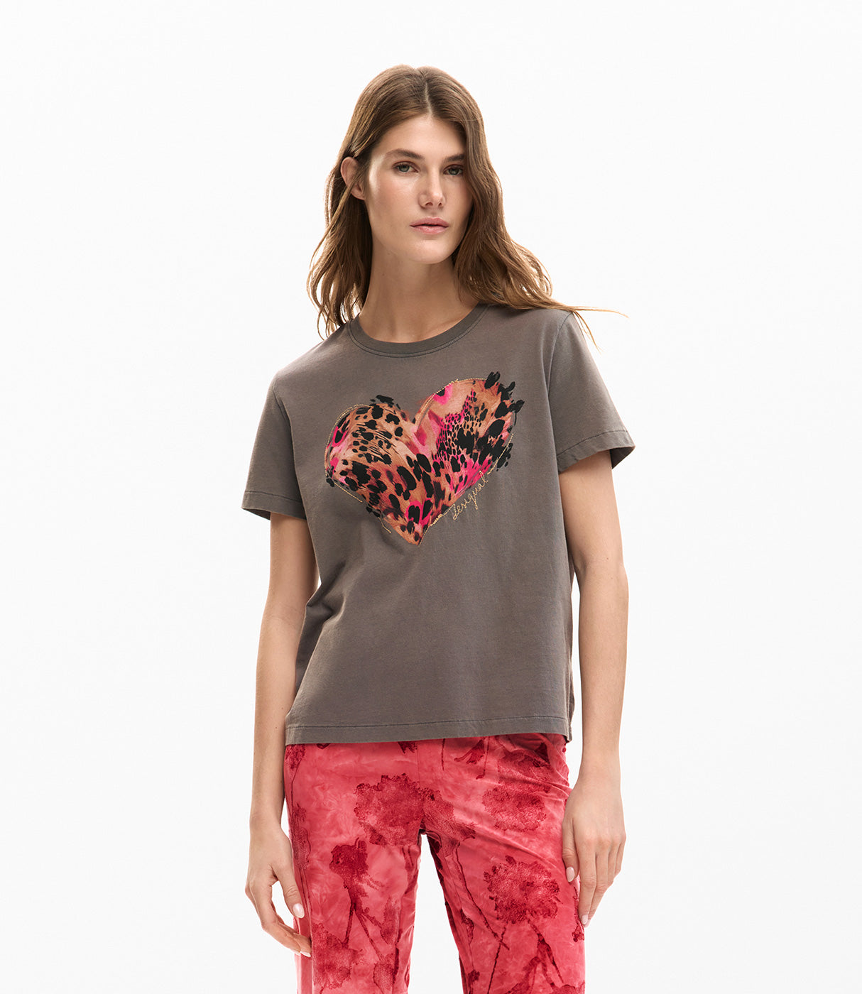 דוגמנית לובשת טי שירט אפורה עם הדפס לב מנומר צבעוני ומכנסיים אדומים מודפסים