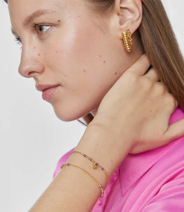 אישה עם עגיל ושרשראות יד בצבע זהב, לובשת חולצה ורודה, צילום תדמית אופנה CHOZEN