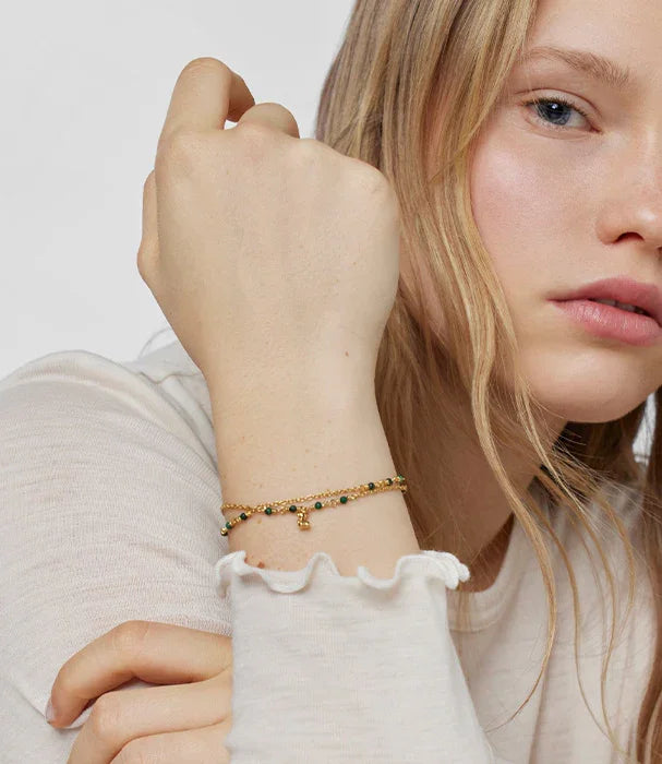 דוגמנית לובשת צמיד זהב עם חרוזים על רקע לבן, תכשיטים אופנתיים CHOZEN