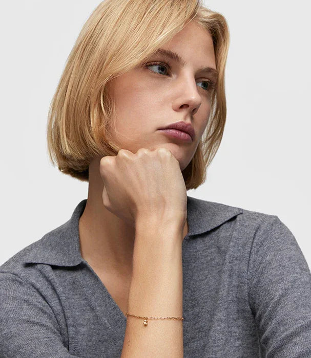 אישה בלונדינית עם שיער קצר לובשת סוודר אפור וצמיד זהב עדין, צילום תדמית לאתר CHOZEN