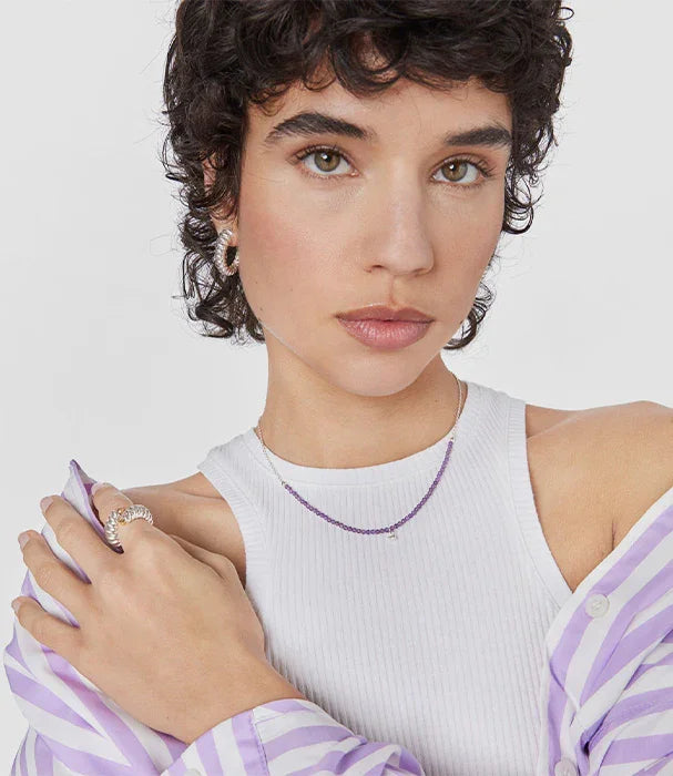 אישה צעירה עם שיער קצר עונדת תכשיטים, עגילים, שרשרת וטבעת, בלבוש אופנתי מבית CHOZEN