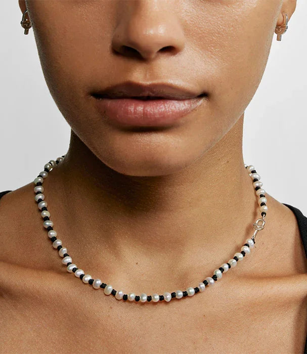 דוגמנית עם שרשרת חרוזים עדינה בשחור ולבן מבית CHOZEN, עגילי חישוק קטנים