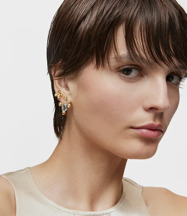 דוגמנית עם שיער קצר עונדת עגילי זהב יוקרתיים של מותג אופנה CHOZEN