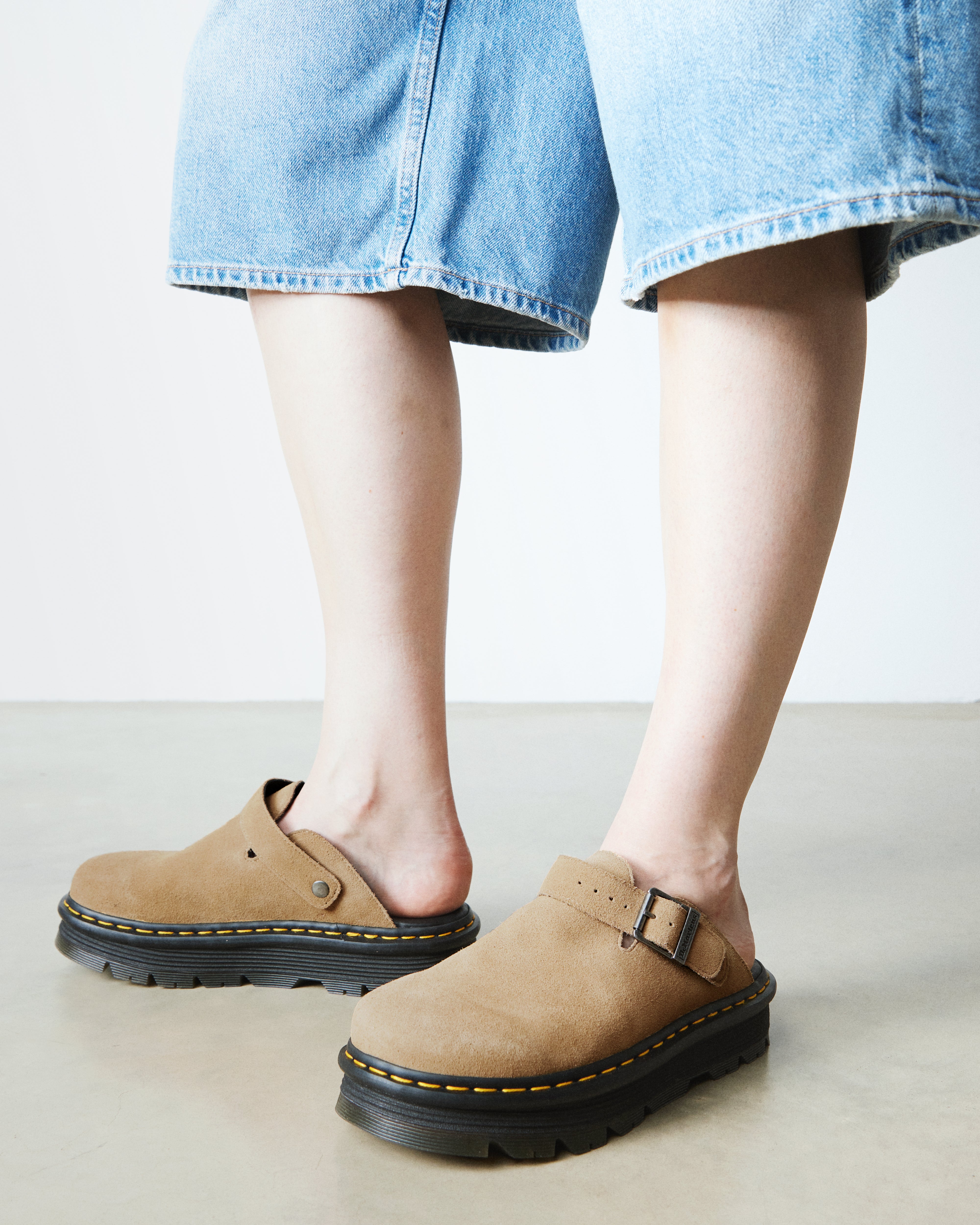 נעליים שטוחות קלאוג בצבע בז' עם רצועה וסוליית פלטפורמה, ג'ינס קצר, רצפת בטון